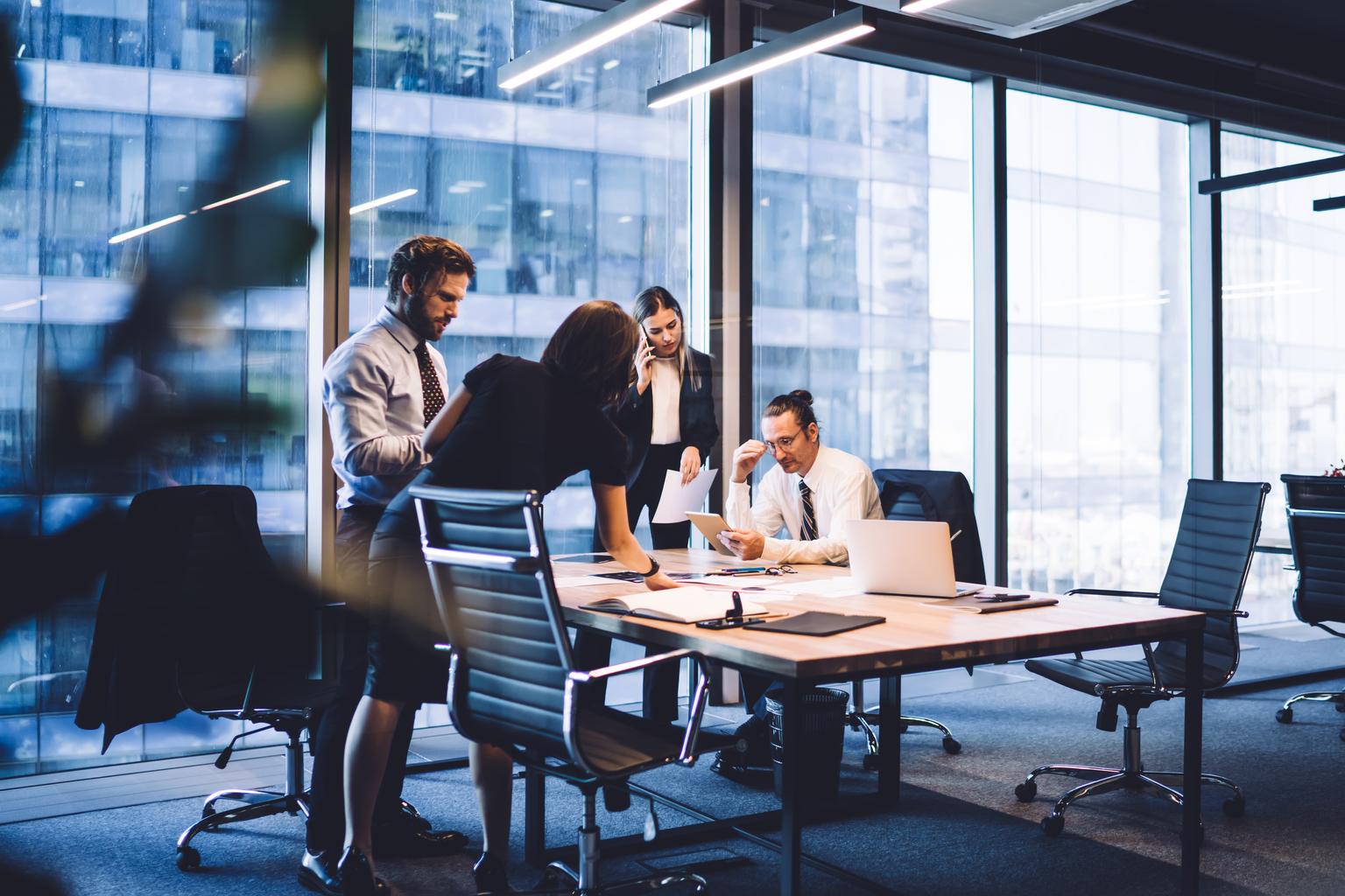 Cooperation process of professional male and female colleagues,business woman in formal suit communicate with operator via smartphone gadget while reading email from partners touch pad during teamwork