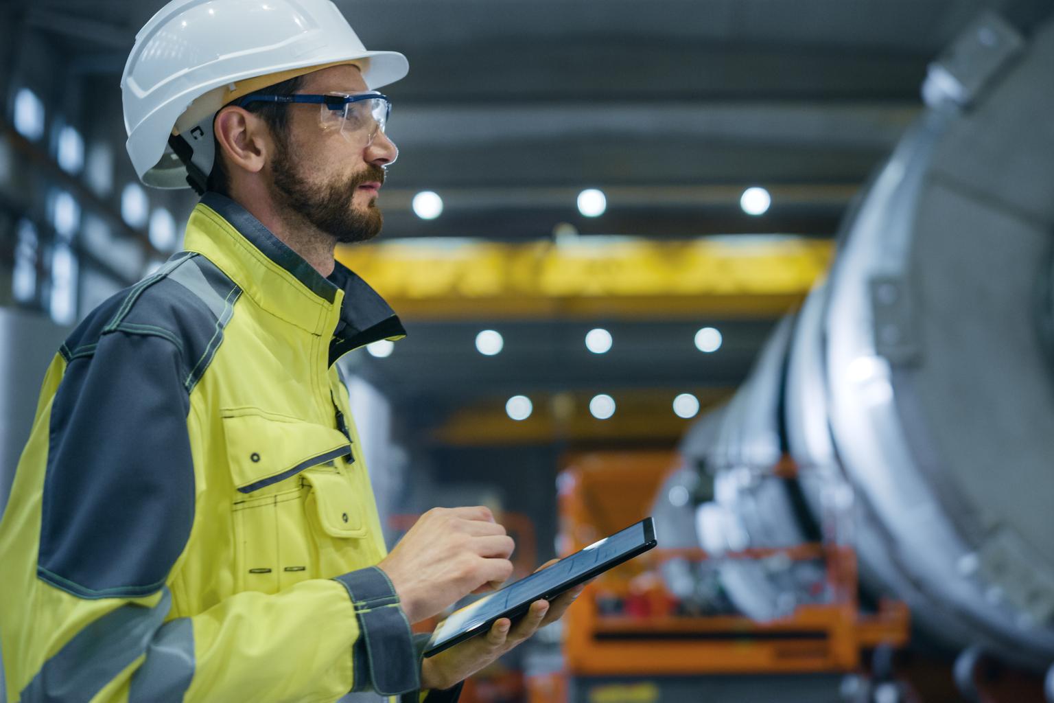 Heavy Industry Engineer in Pipe Manufacturing Factory, Use Digital Tablet Computer. Facility for Construction of Oil, Gas and Fuel Pipeline Transportation Products. Side View