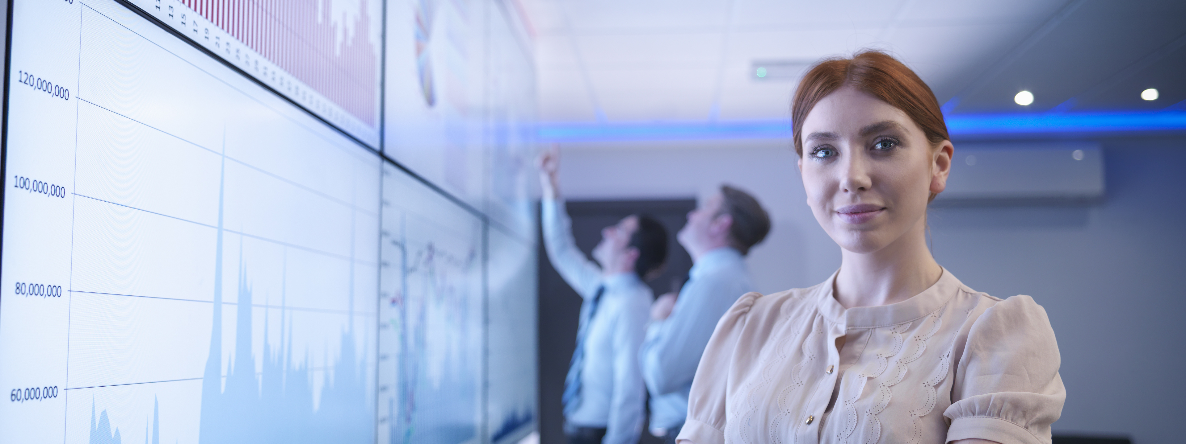 Businesswoman in front of graphs on screen in meeting room, portrait