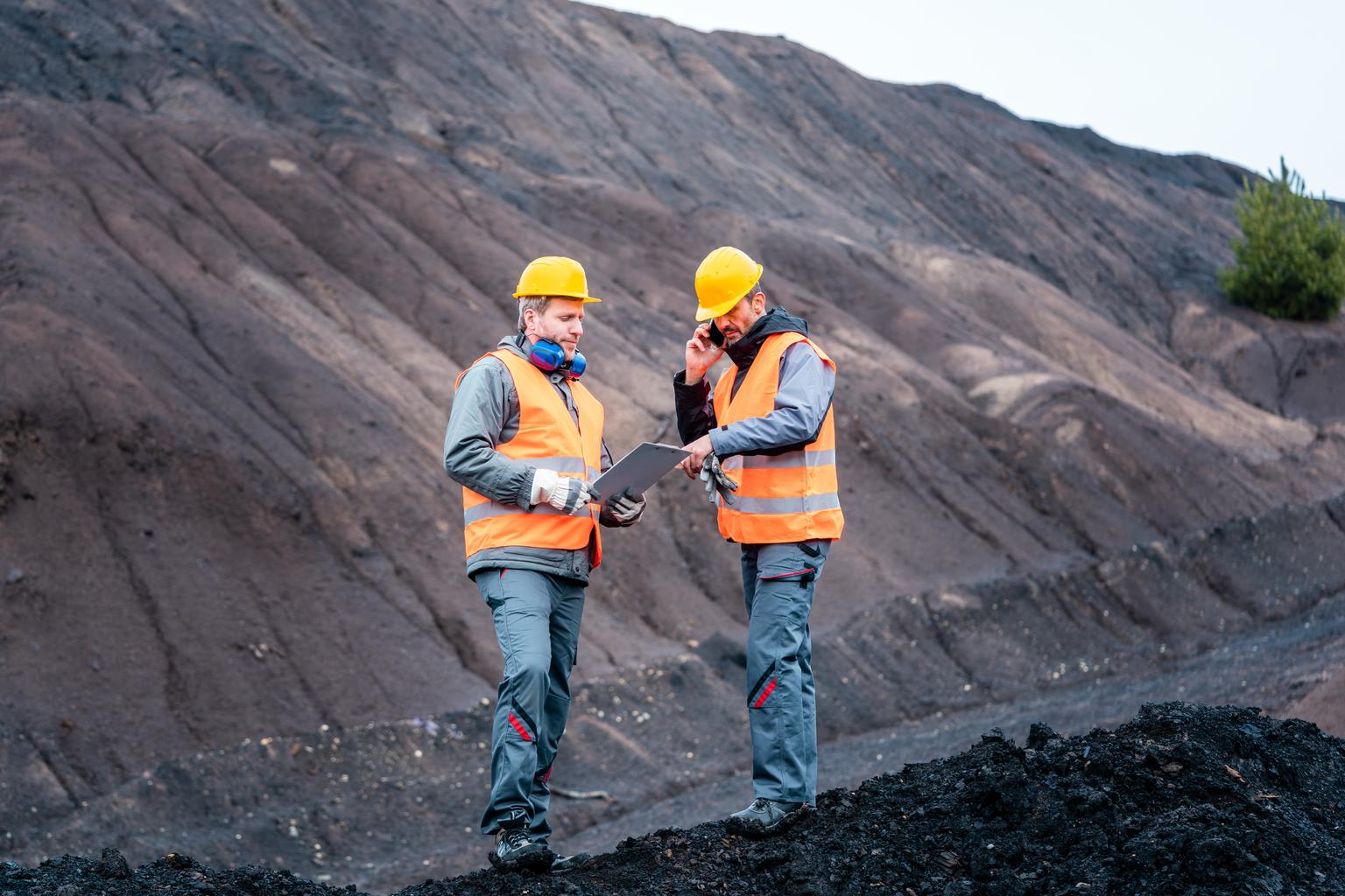 Workers standing in open-cast mining operation pit