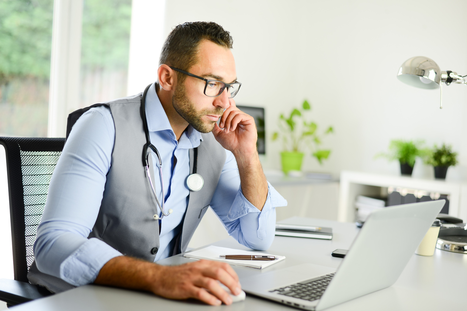 Male doctor on laptop in clinic office