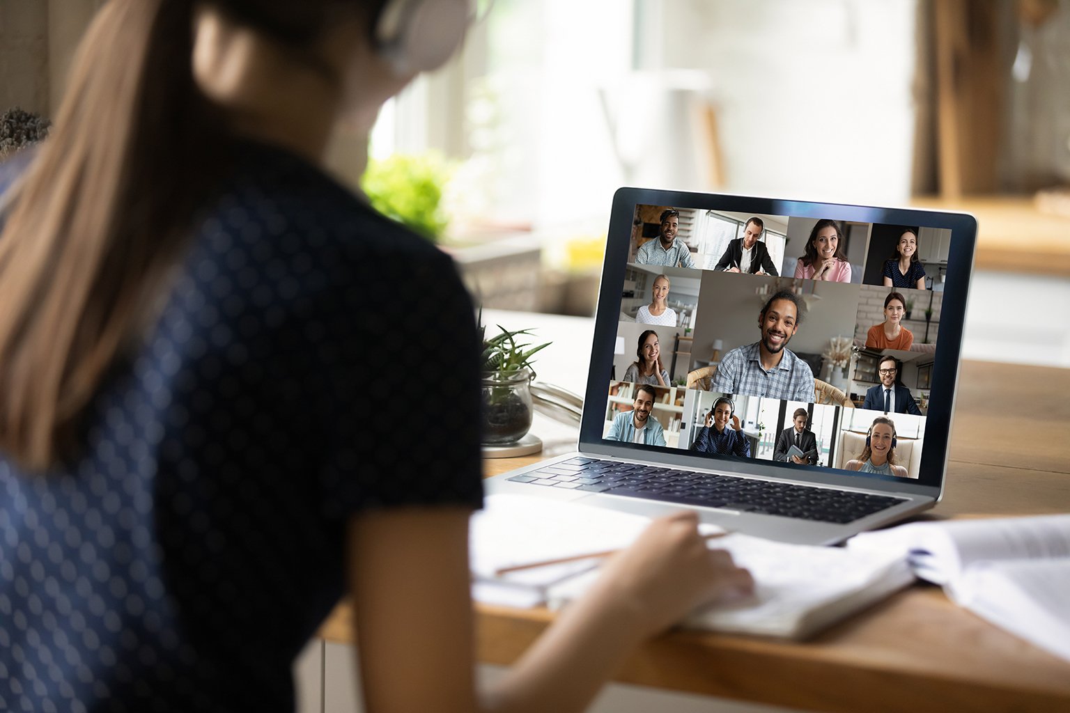 Close-up rear view of female student at home on computer engaged in group video call