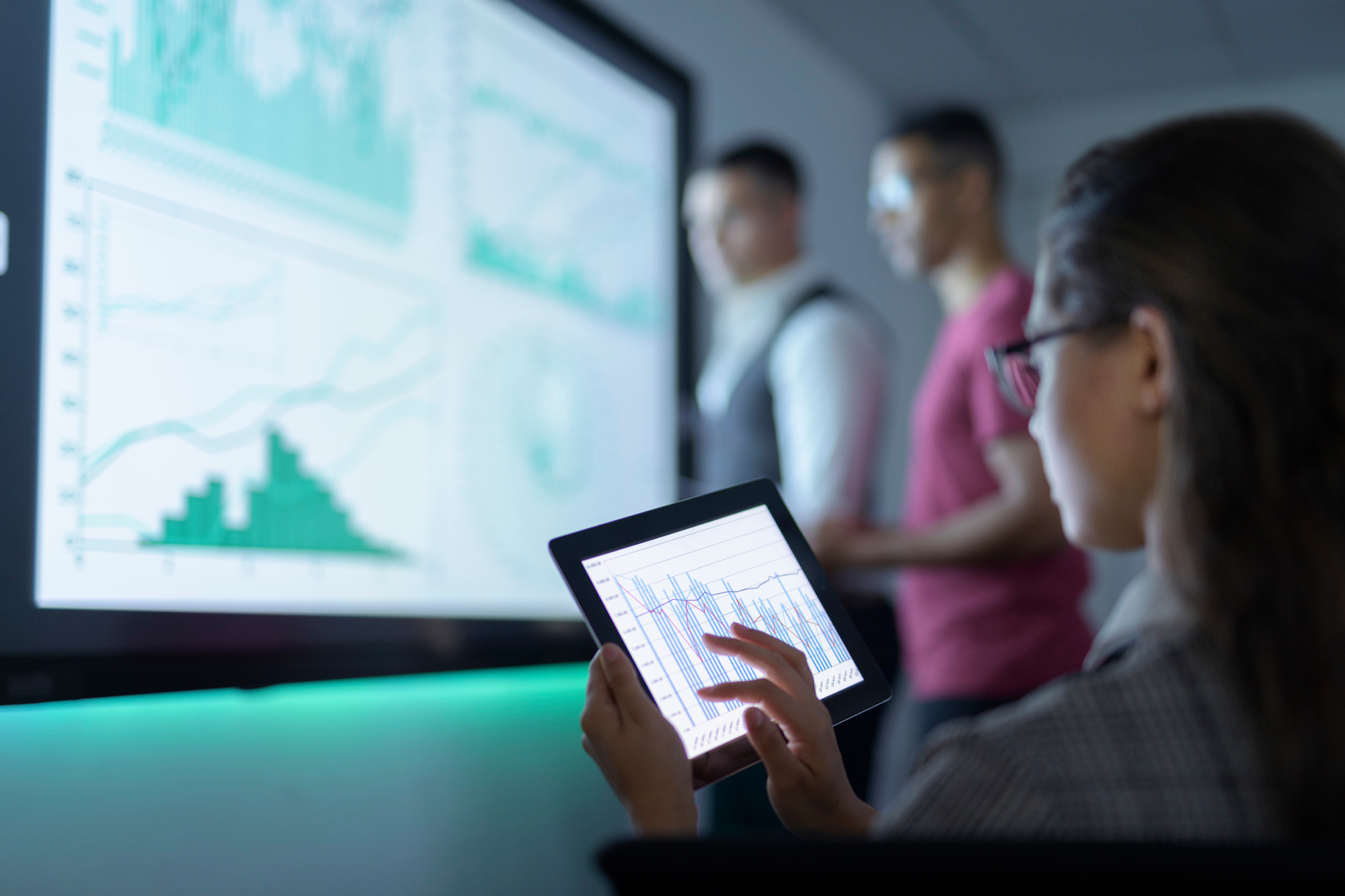 Businesswoman viewing graphs on digital tablet in meeting.