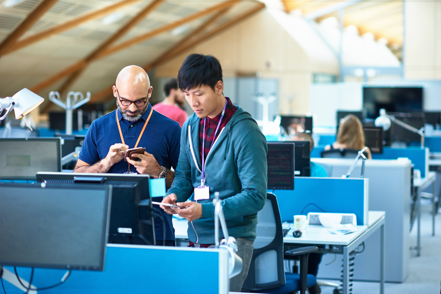 Two men using mobile phones in modern office.