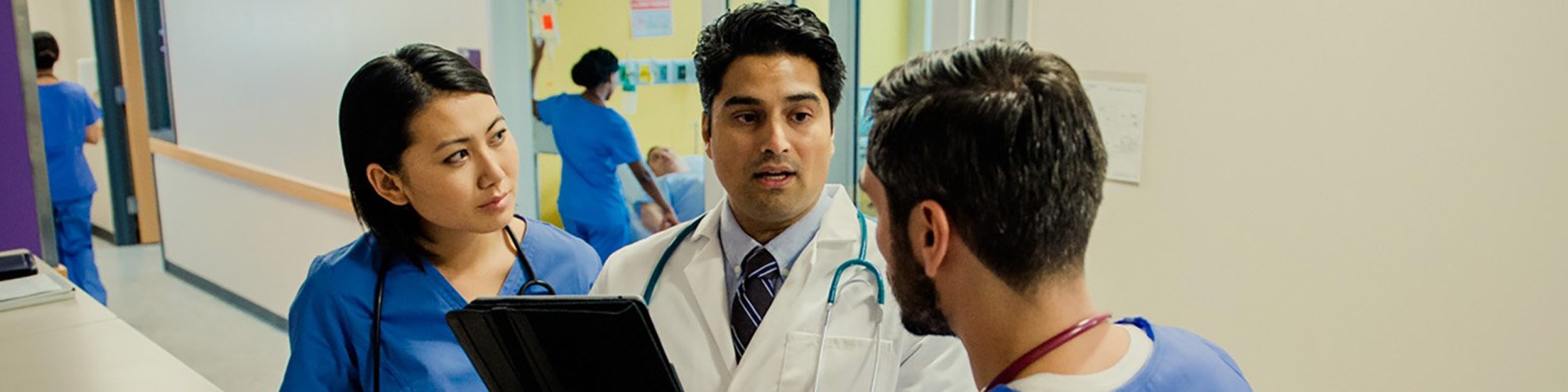 Doctor speaking with male and female nurses at nursing station