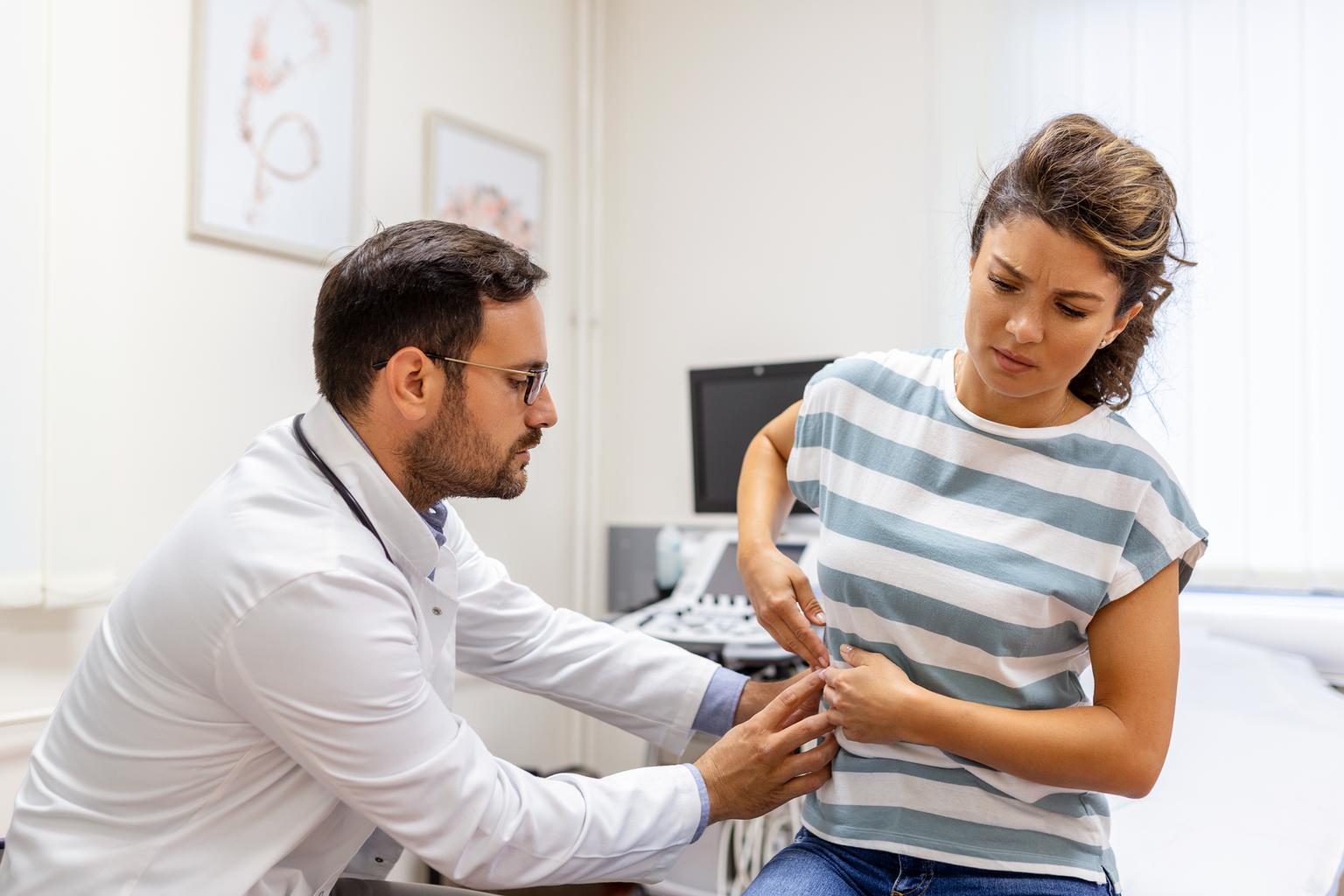 Male doctor assisting female patient with kidney health concern in clinic