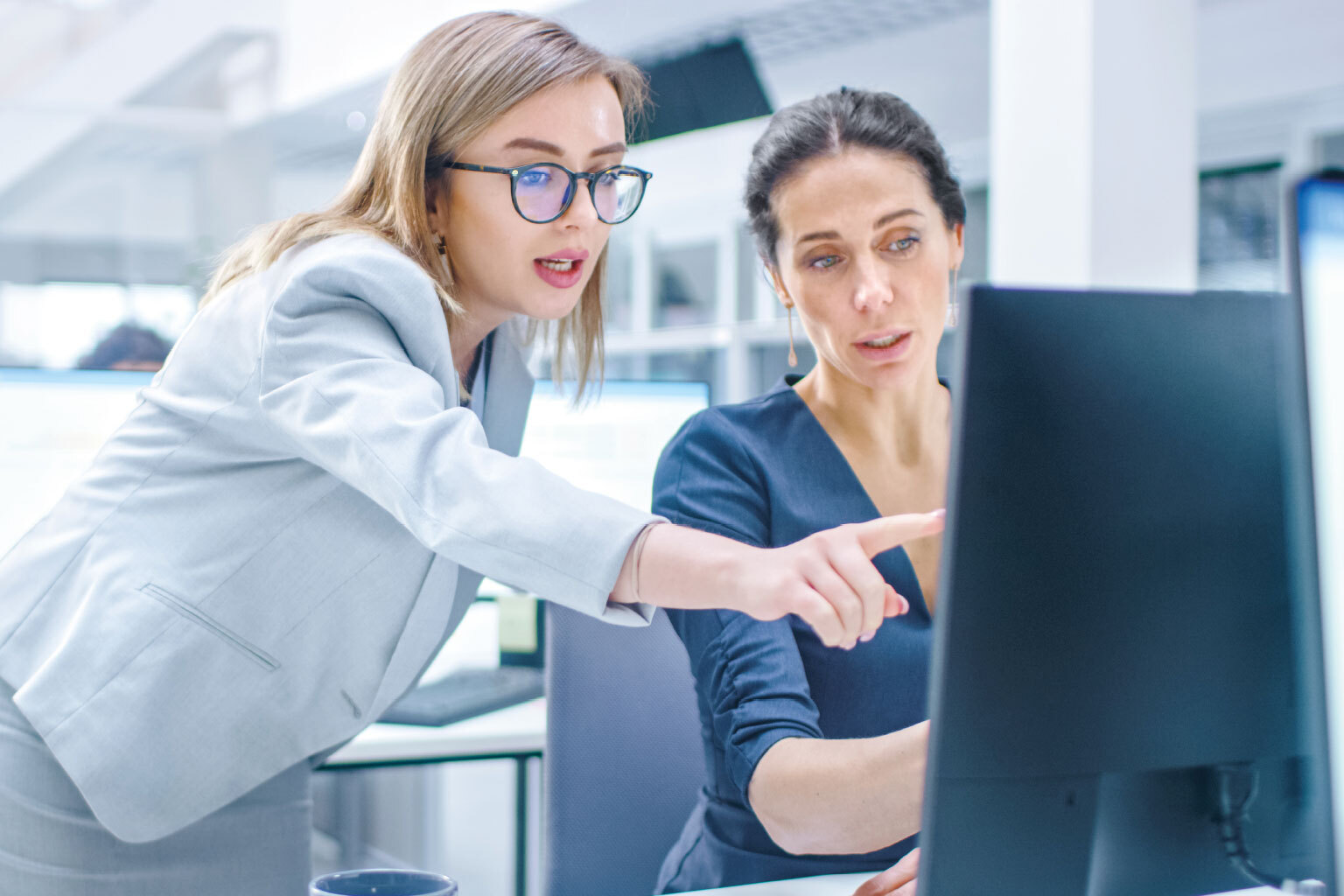 Female Manager Explains Task to Businesswoman who Works on Desktop Computer