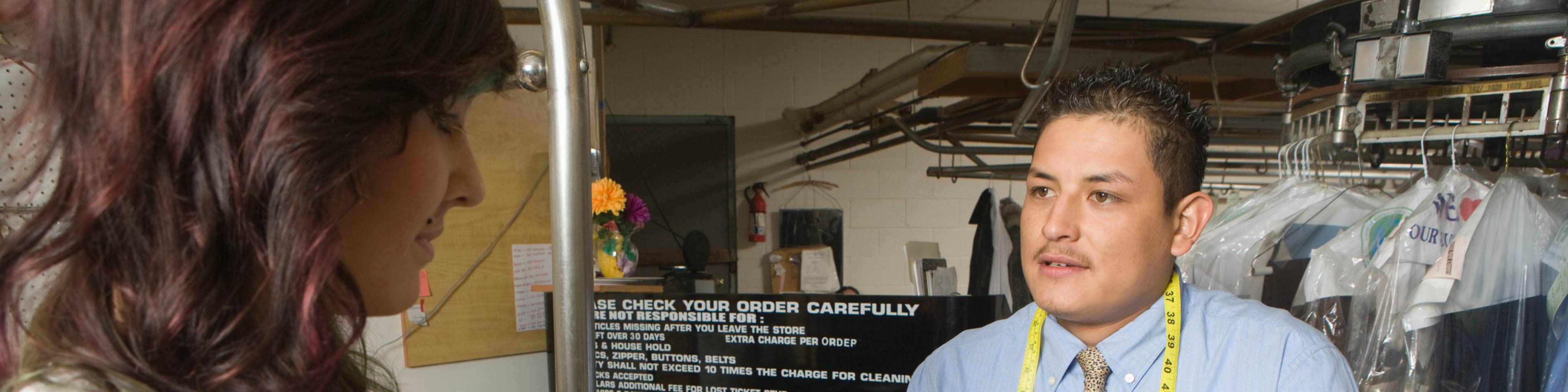 A man working in a dry cleaner, helping a customer