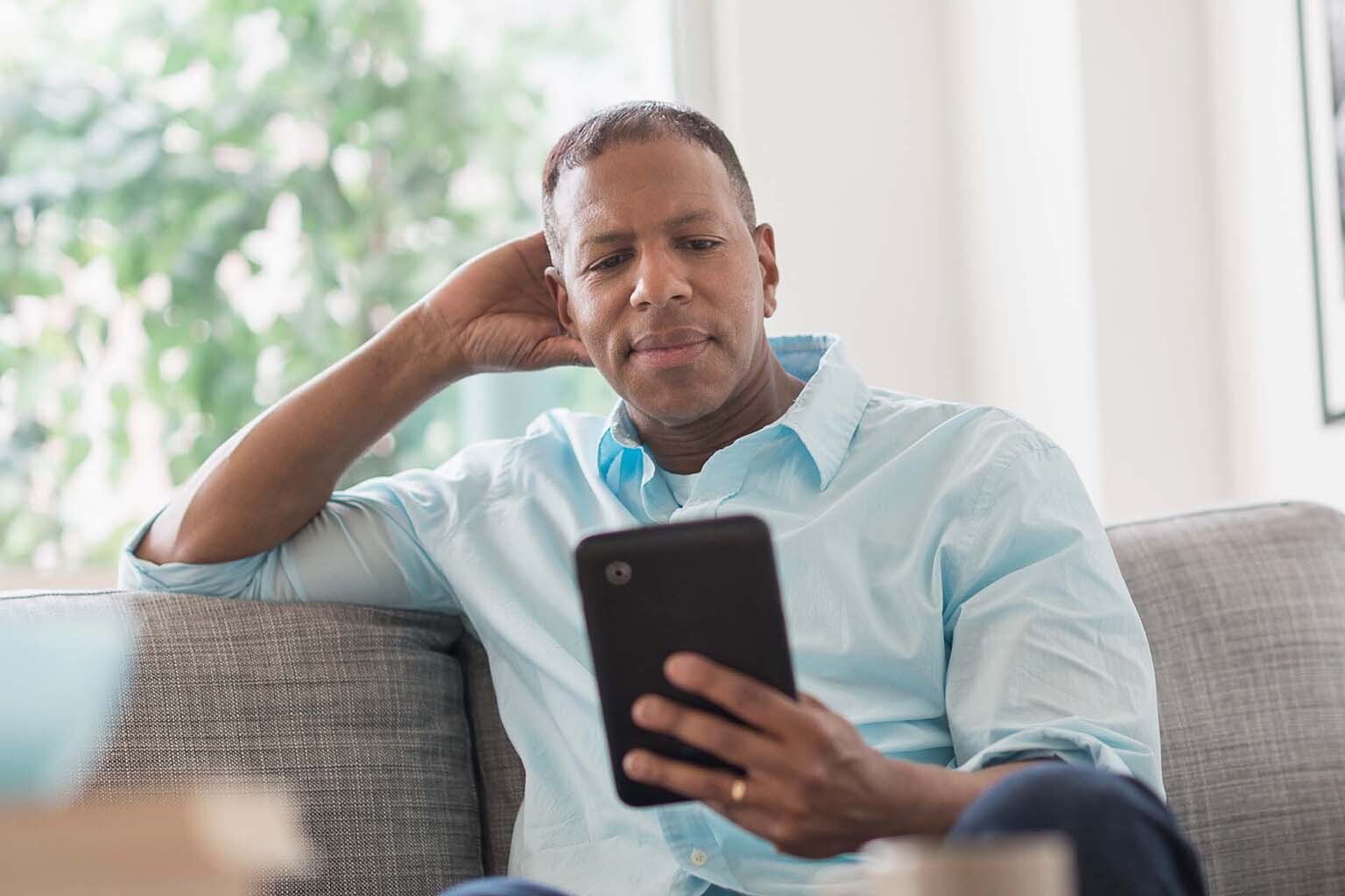 male on couch using tablet