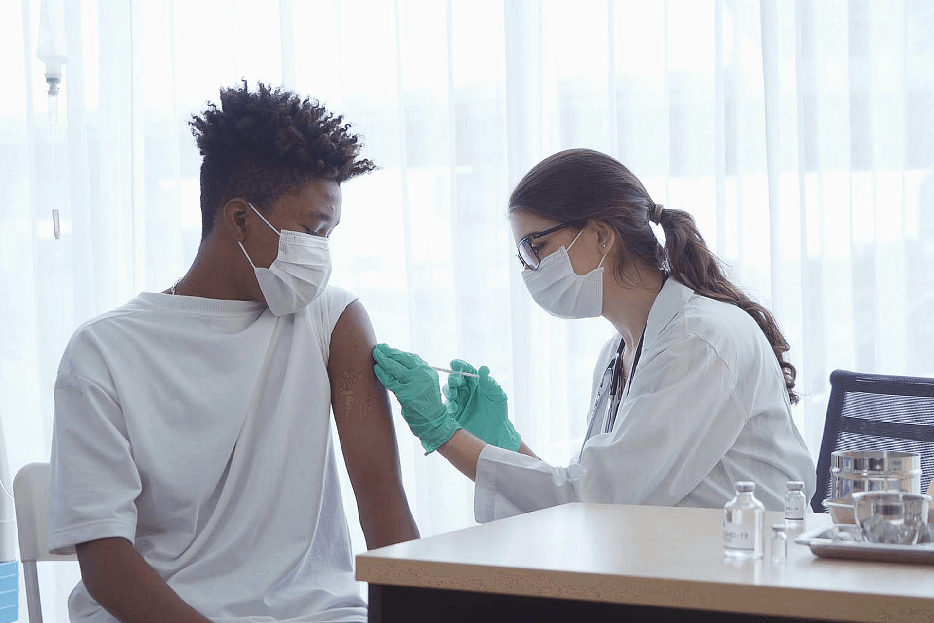 Medical professional wearing PPE, giving vaccine injection to patient