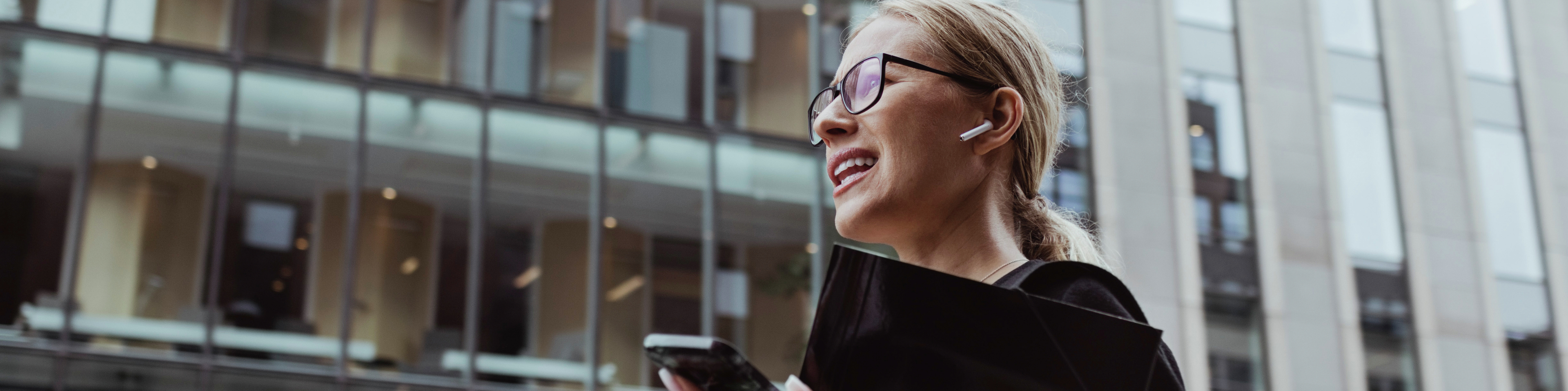 Low angle view of businesswoman talking through in-ear headphones in city