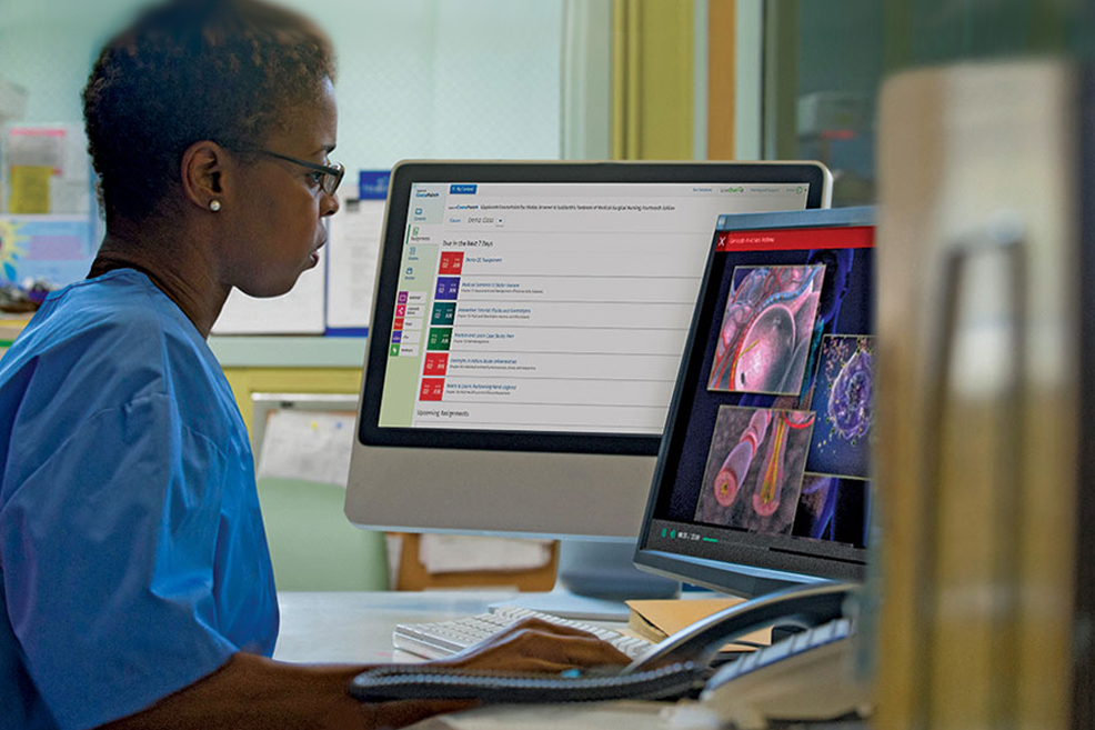 Nurse sitting at a double monitor computer with one showing CoursePoint