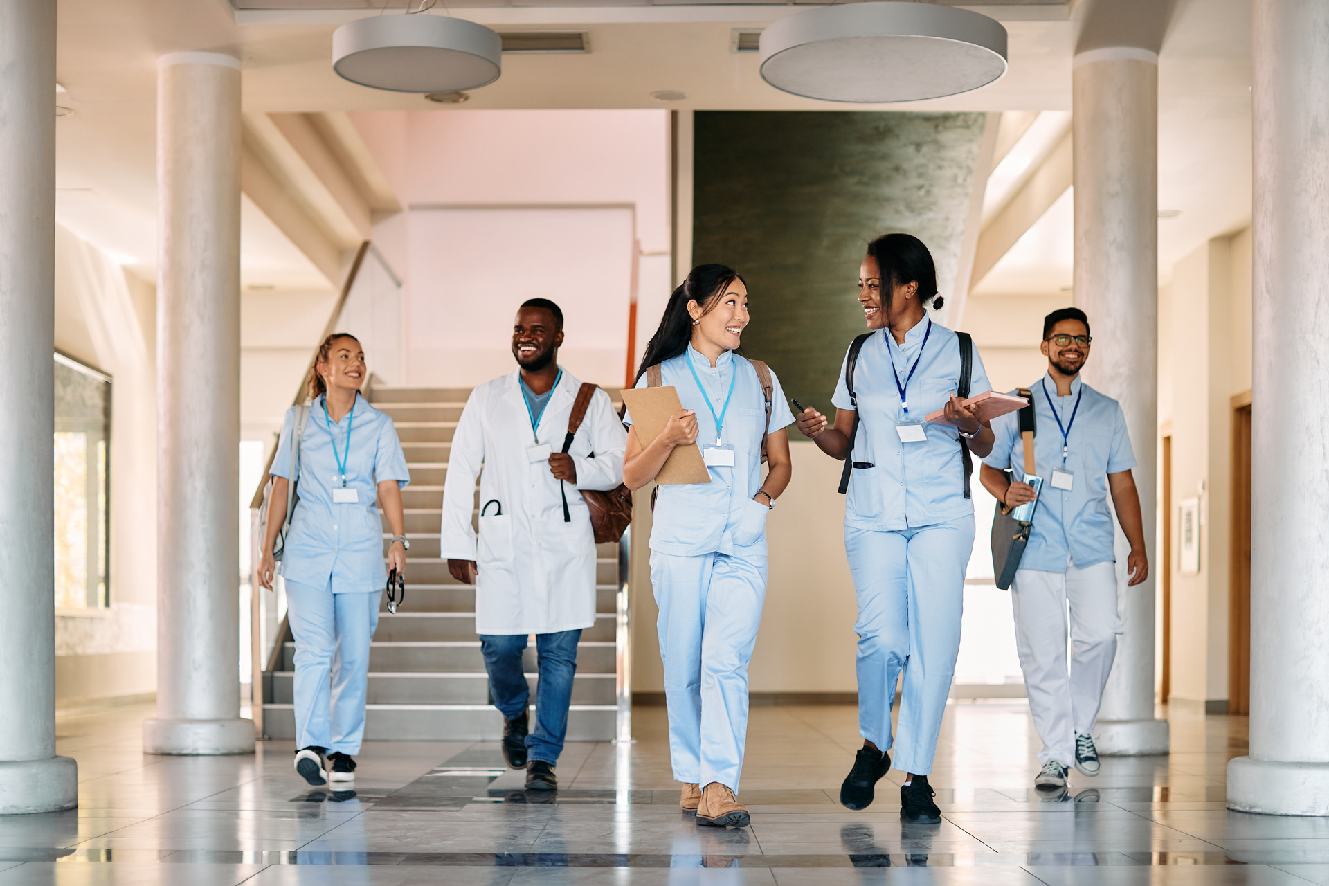Group of happy medical and nursing students walk through hallway and talk.