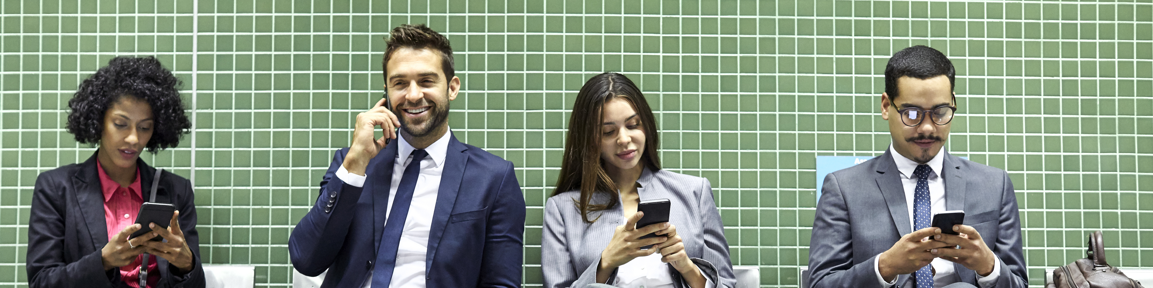 Full length of professionals using smart phones while waiting at subway station