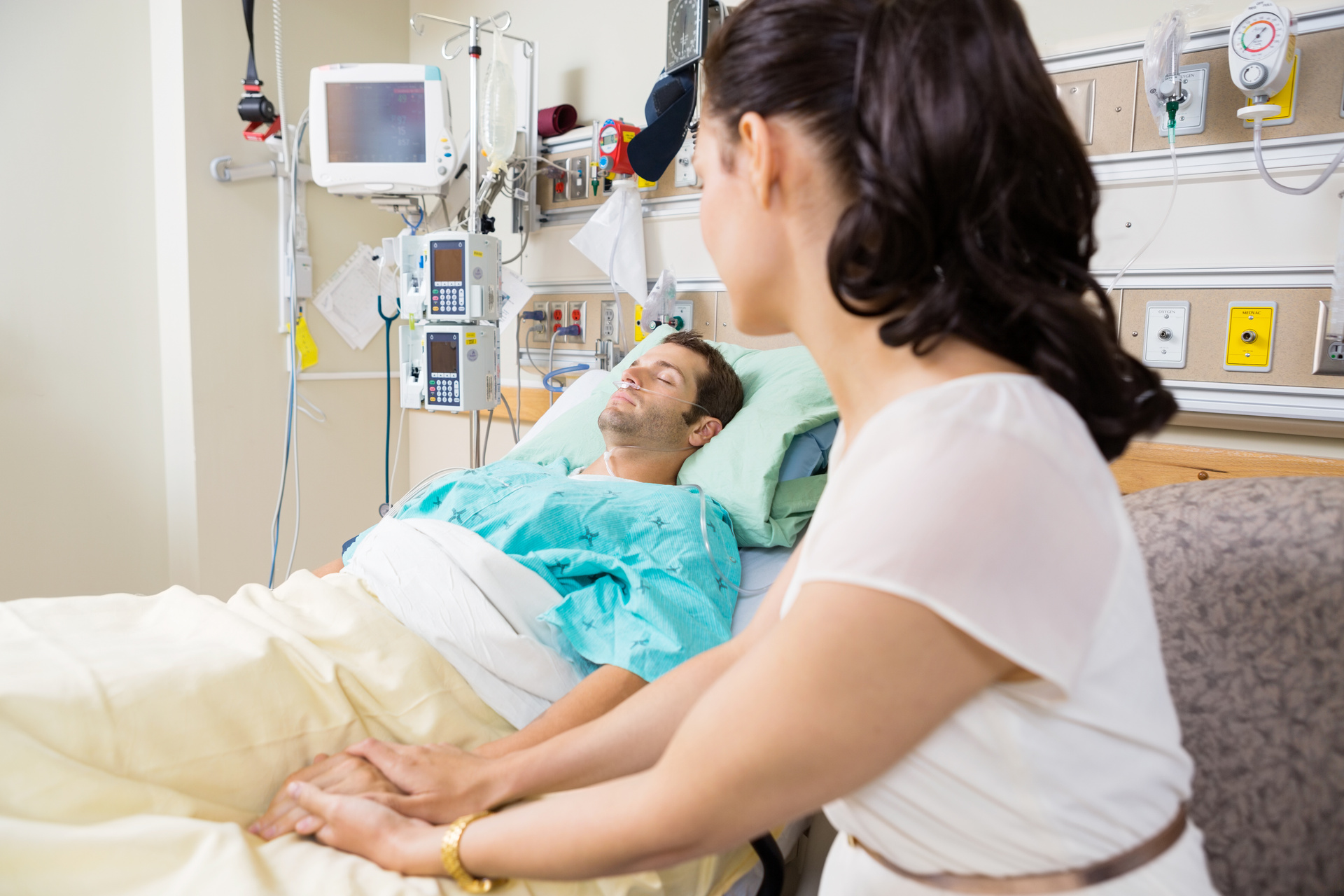 Woman holding ICU patient's hand