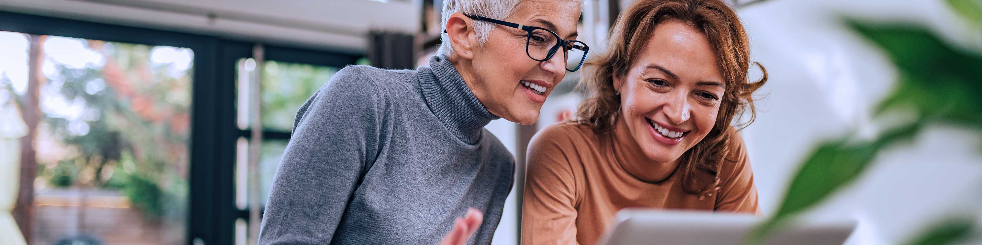 two women smiling looking at laptop