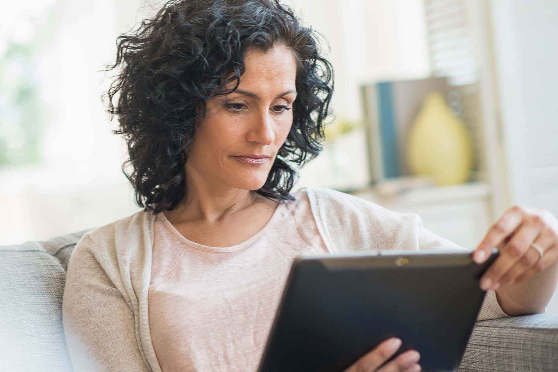 woman on couch using tablet