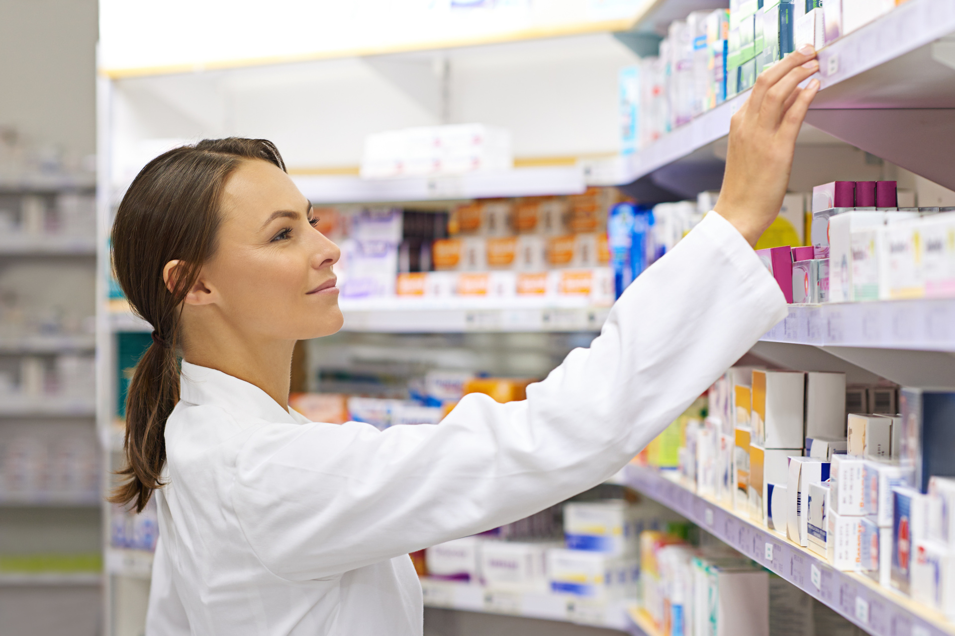 Pharmacist selecting medicine from shelf
