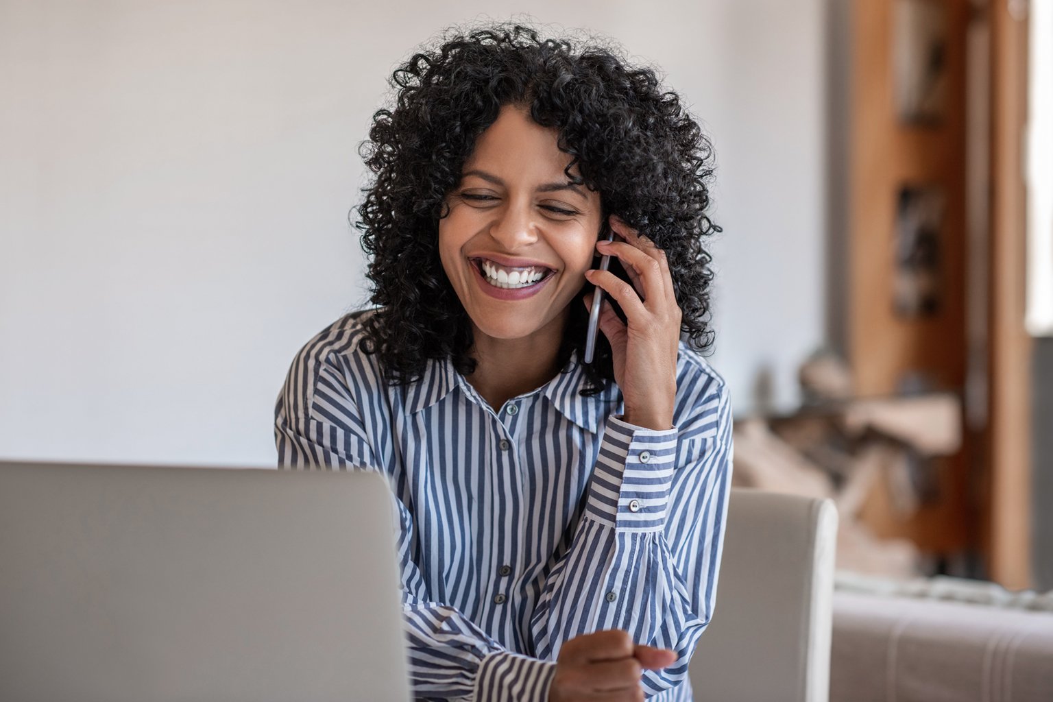 Laughing female entrepreneur talking with a client on cellphone