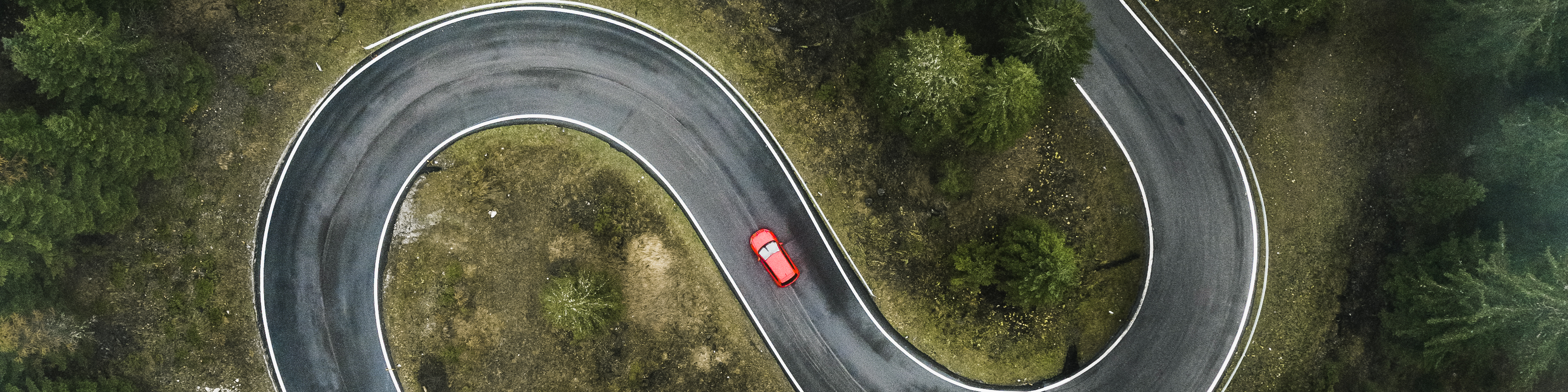A car driving on a winding forest road seen from directly above, Dolomites, Italy,
