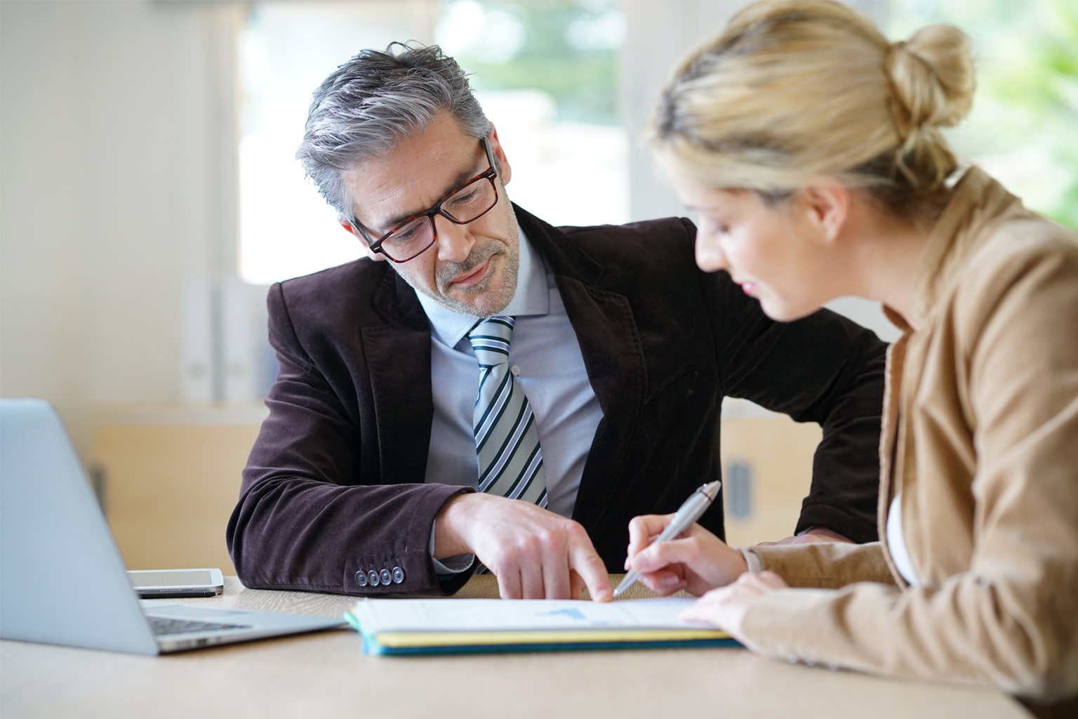 a man and a blonde woman looking at docs