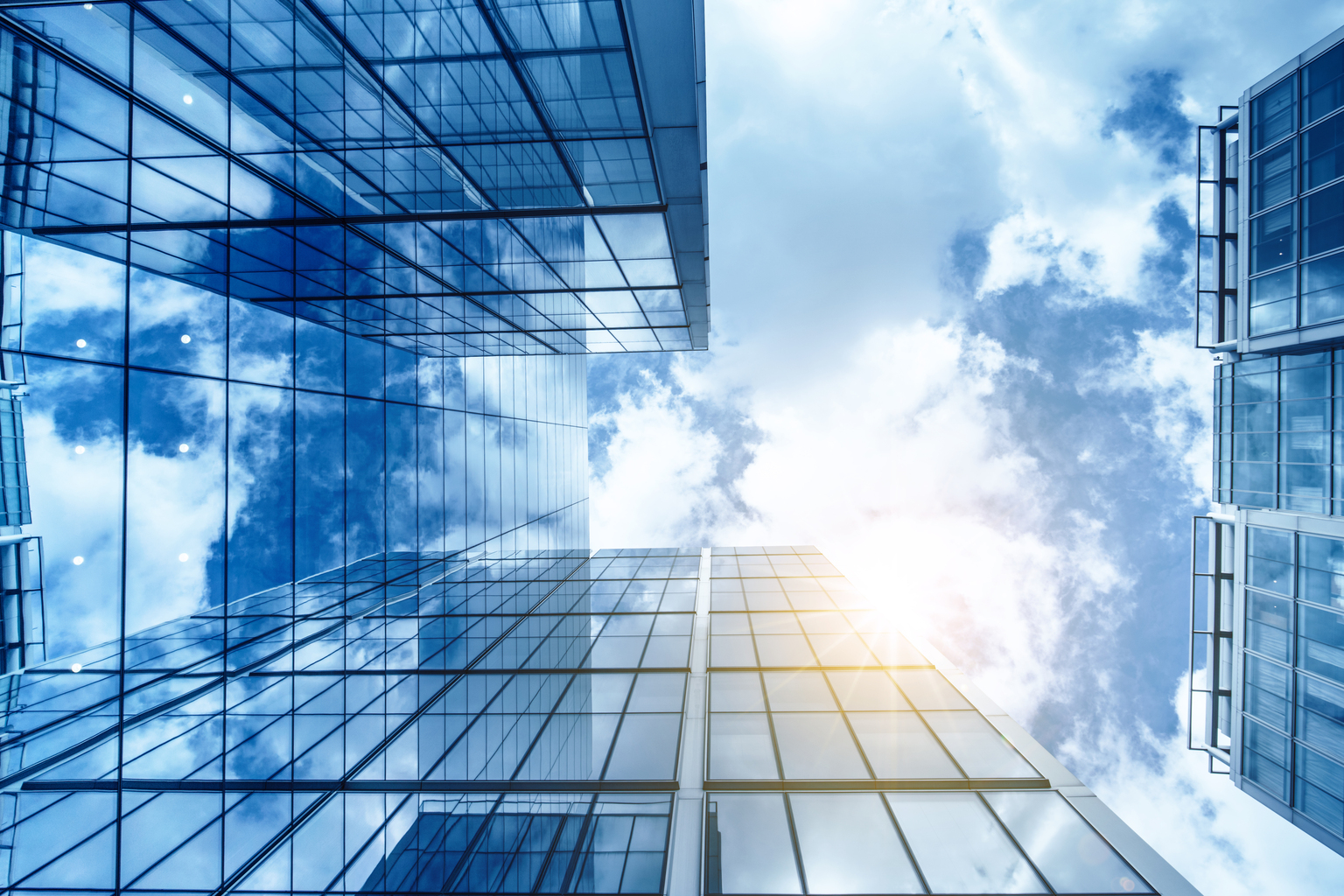 view of a contemporary glass skyscraper reflecting the blue sky