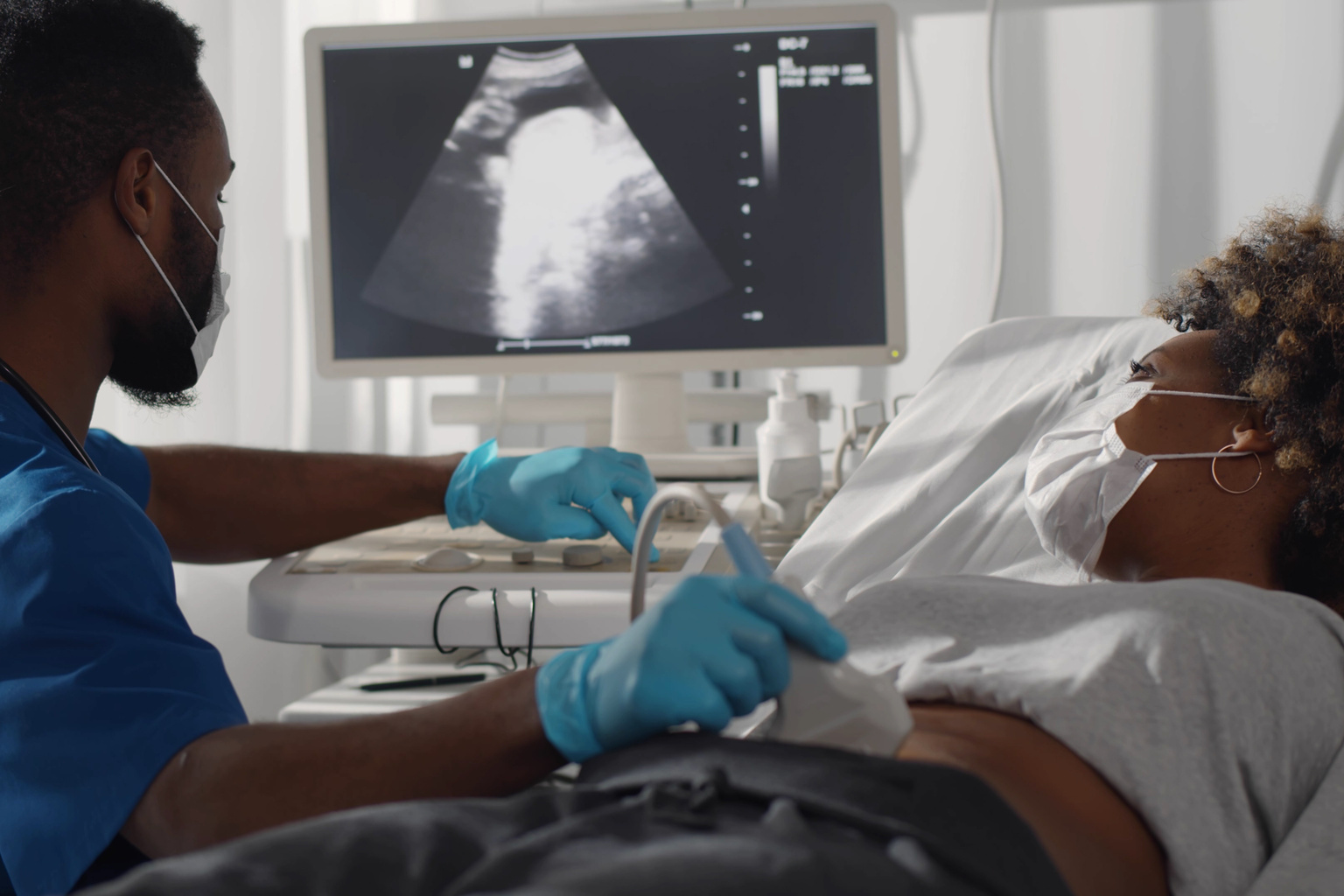 Black nurse technician giving ultrasound to pregnant Black patient