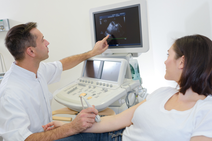 Doctor preforms ultra sound on patient's right arm. 