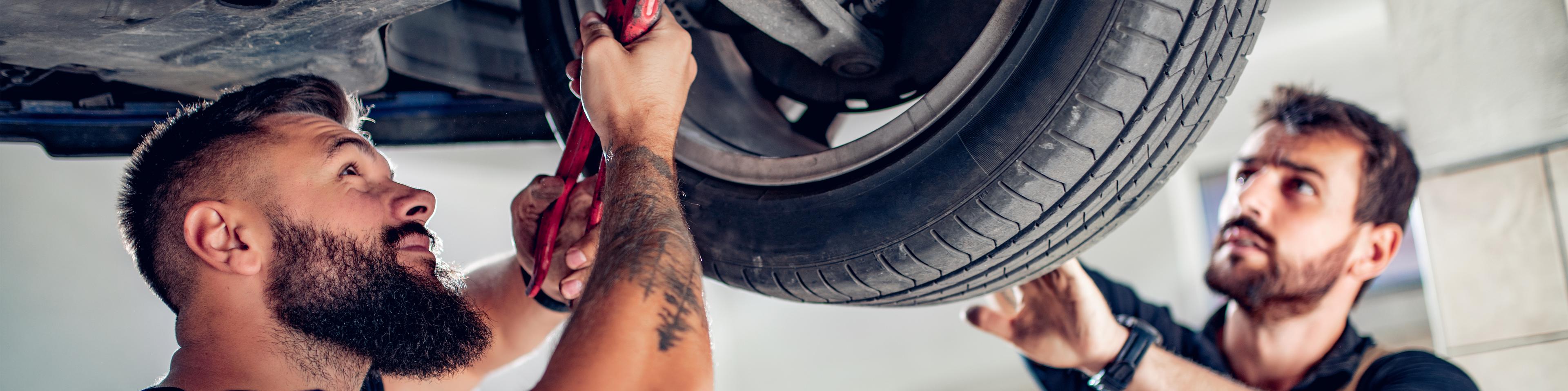 Two auto mechanics working on a car that is on the lift