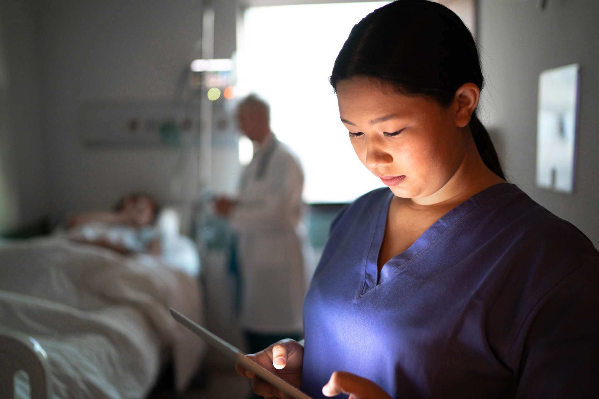 Female nurse using digital tablet at hospital room