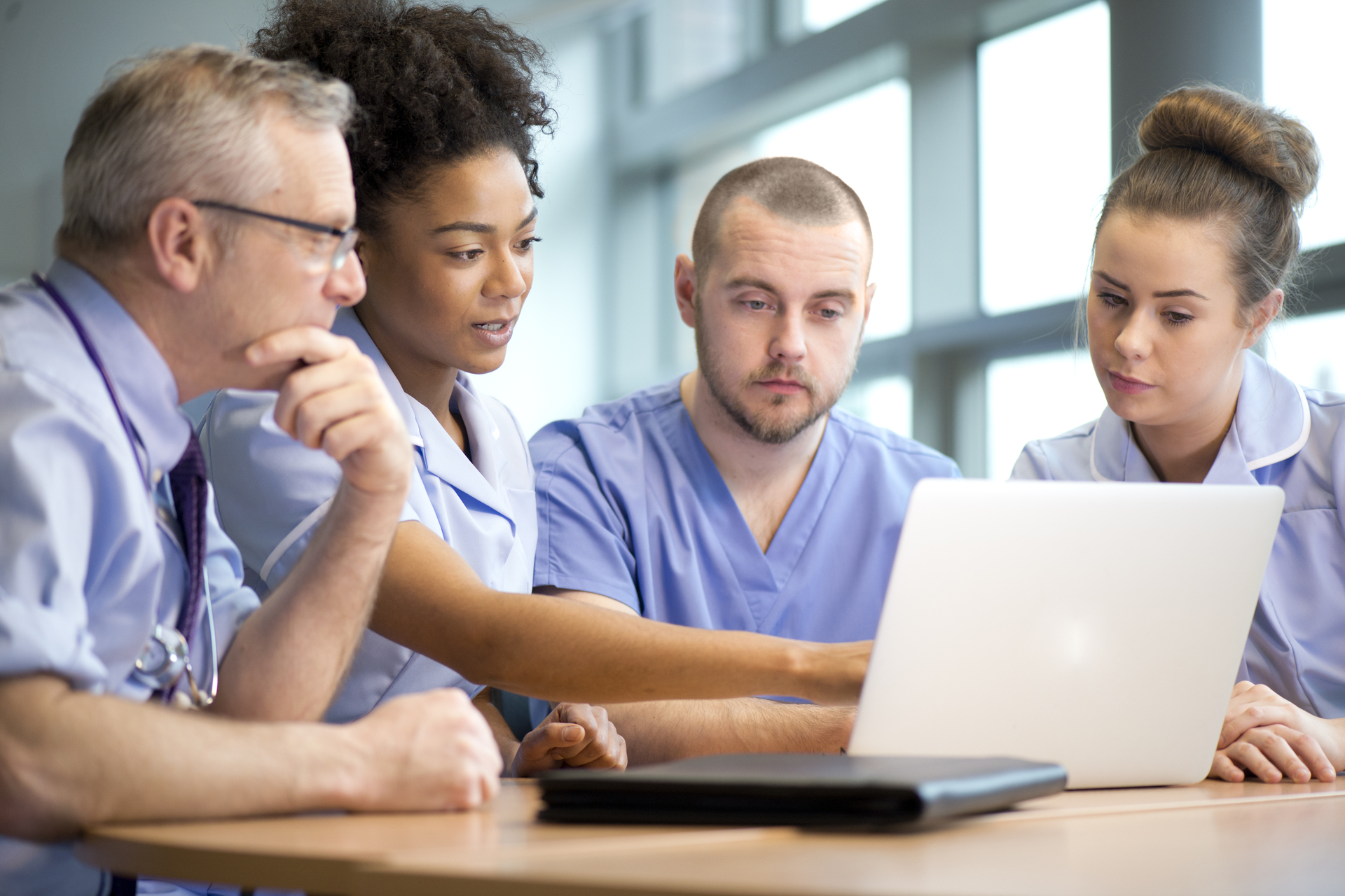 Group of medical students and instructor review materials on a laptop