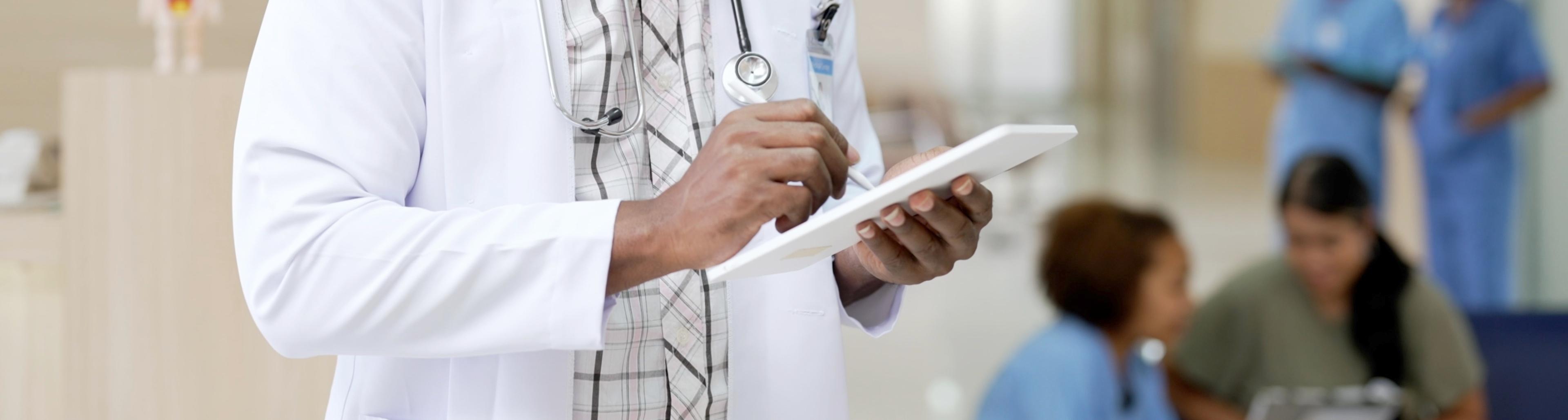 Black doctor making notes on tablet in hospital