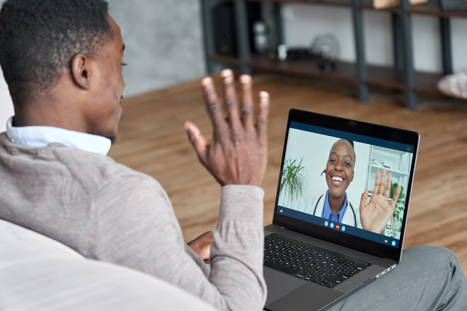 Clinician virtually consulting young man during online appointment on laptop at home