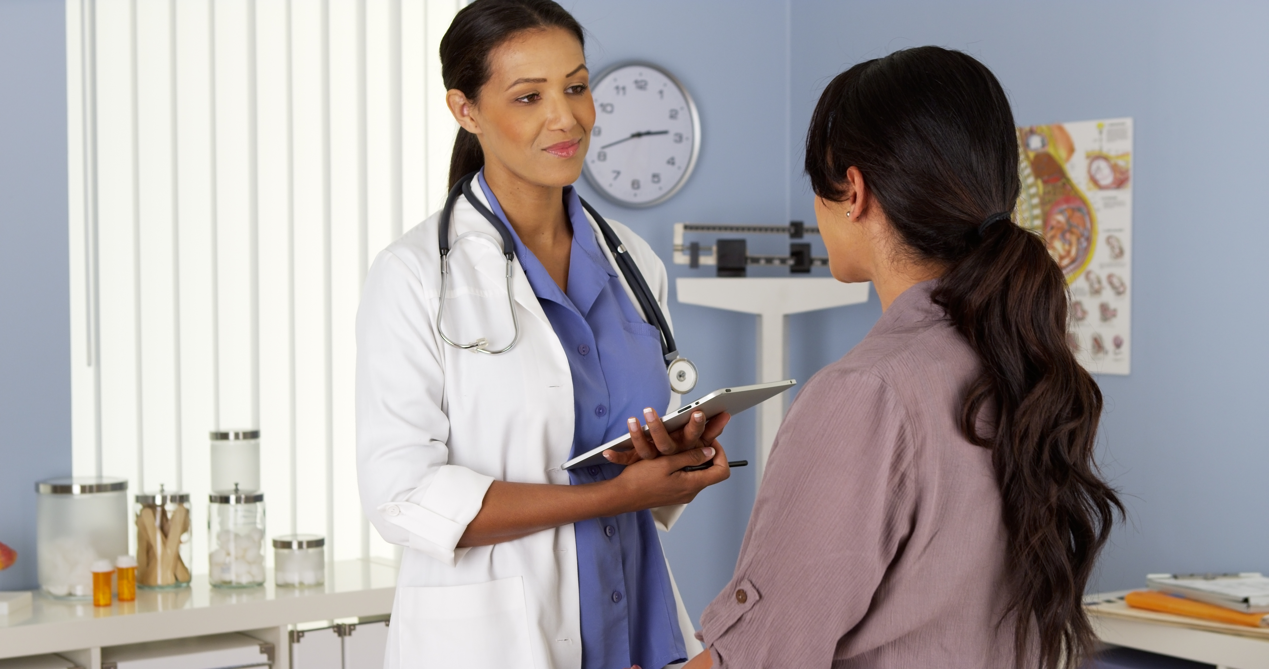 Female doctor with tablet speaking to female patient