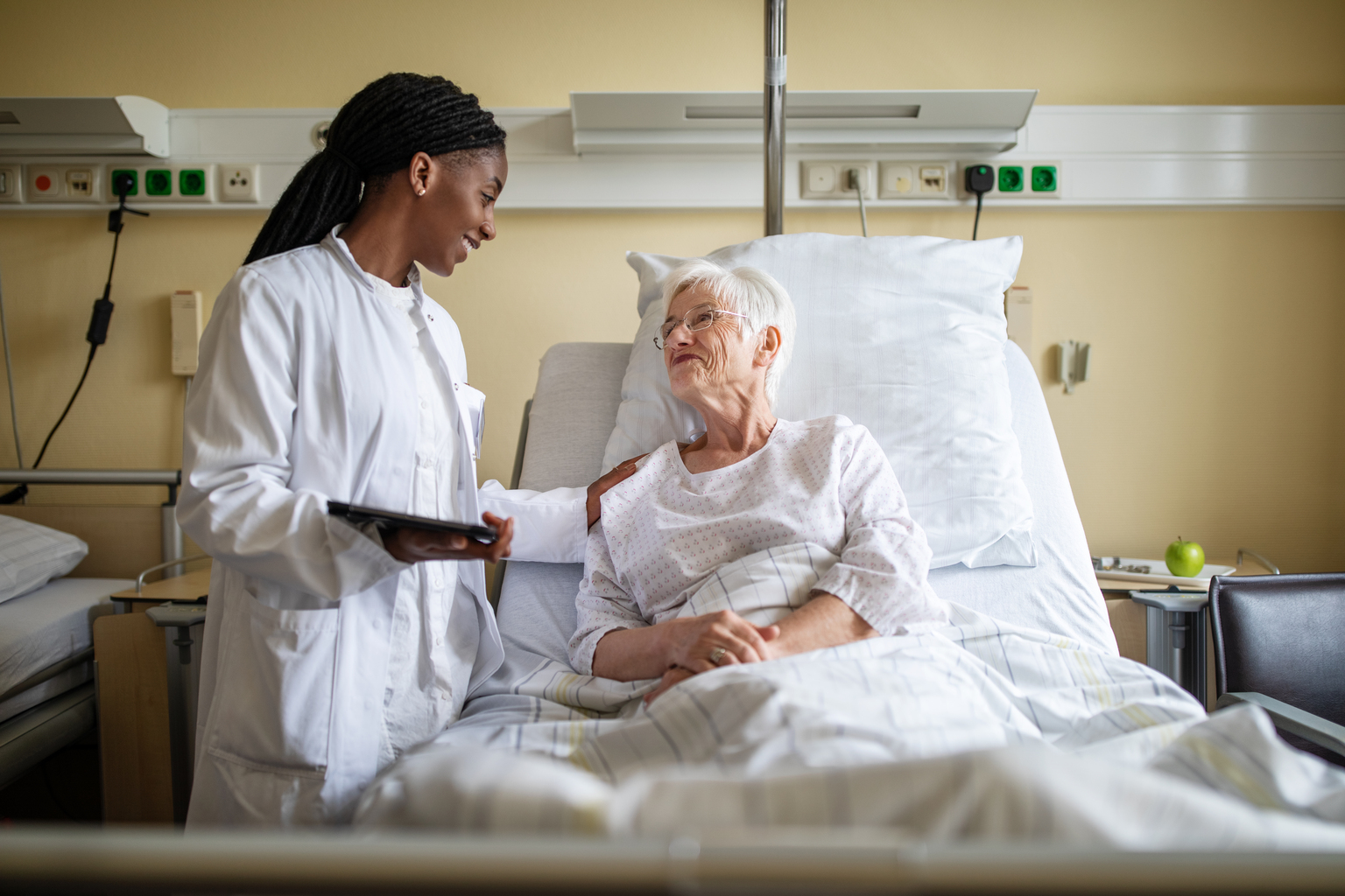 Young African doctor consoling senior patient during visit.