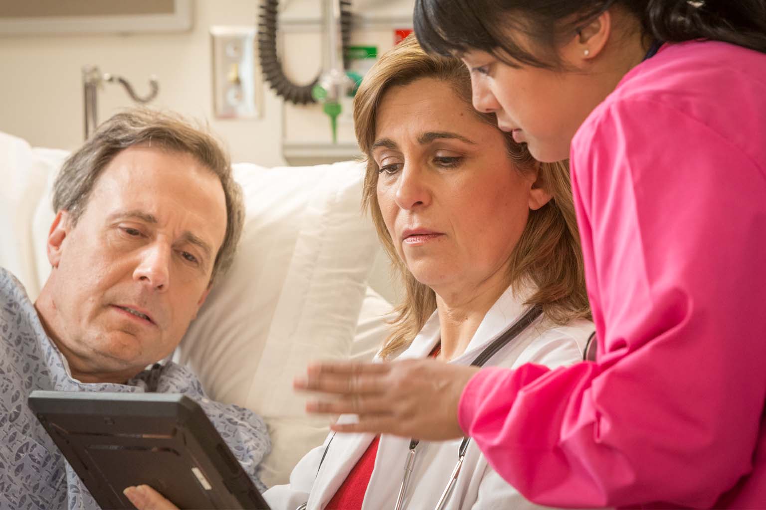 clinician and nurse with tablet talking to patient