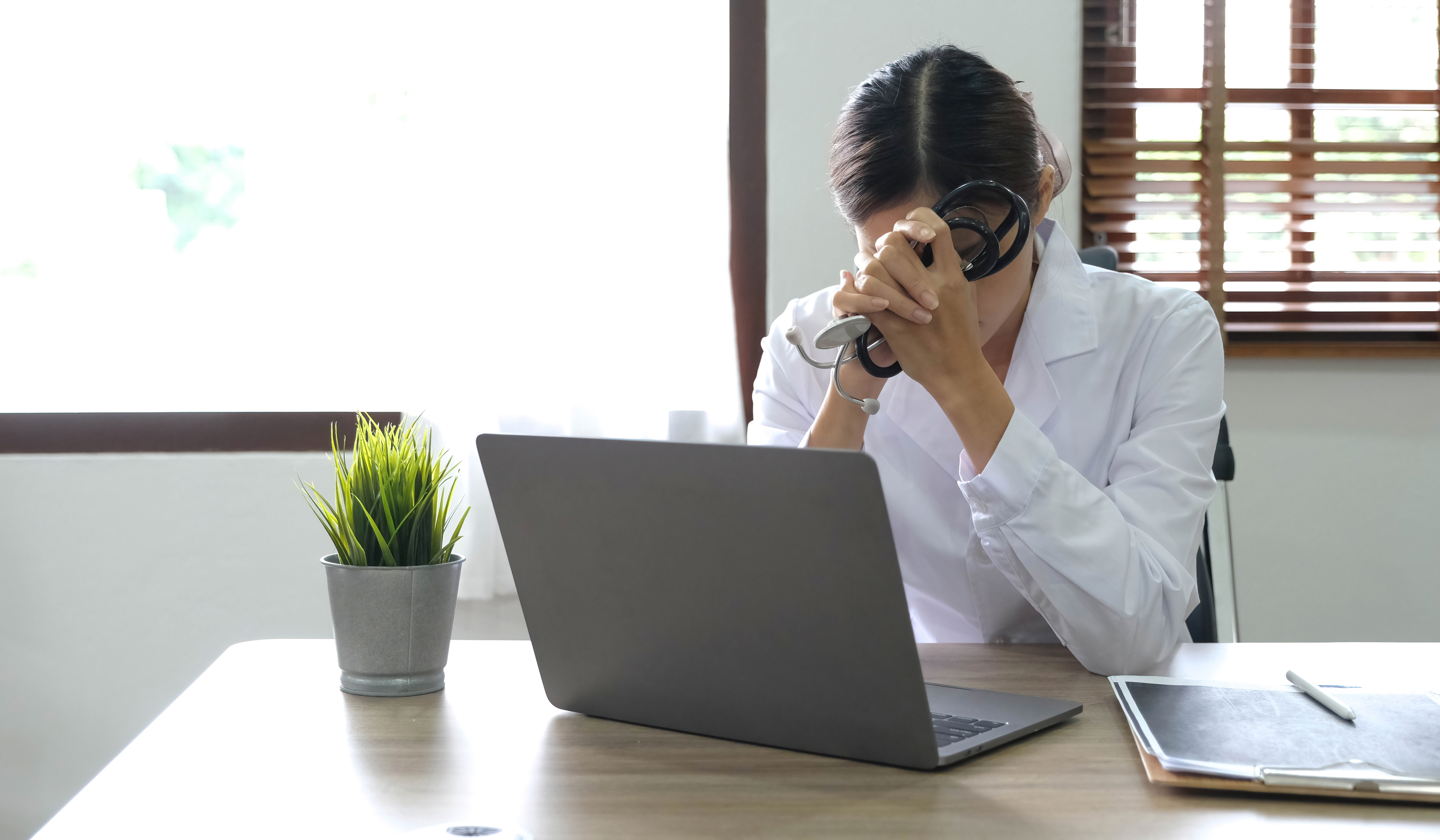 Health care professional sitting at desk, slumped in frustration