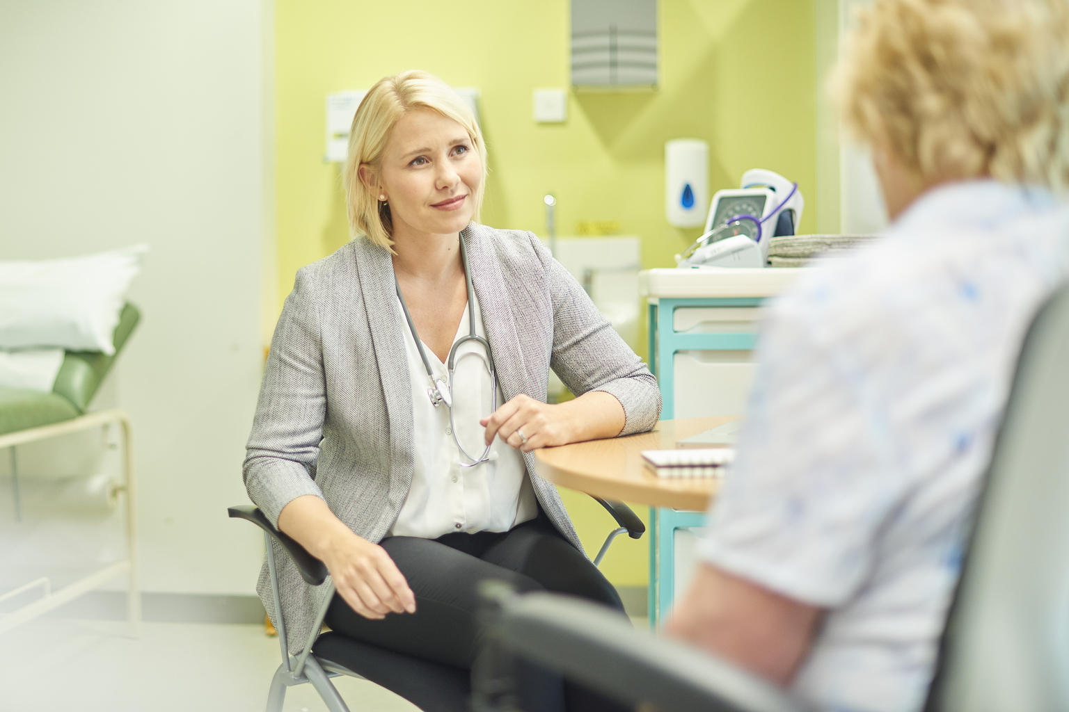 Female doctor talks to a senior patient in the clinic and writes out a prescription