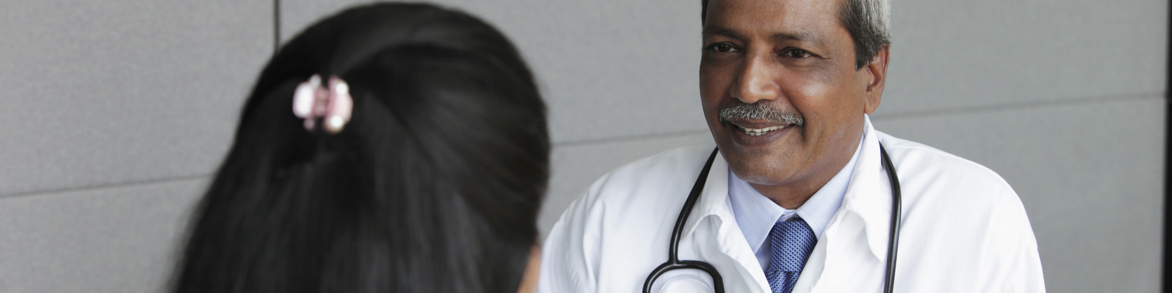 Doctor sitting with and smiling at patient while taking notes