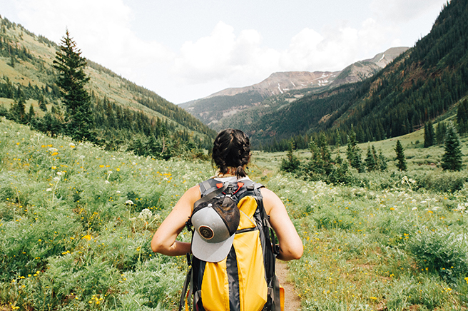 Woman with backpack hiking through mountainous area