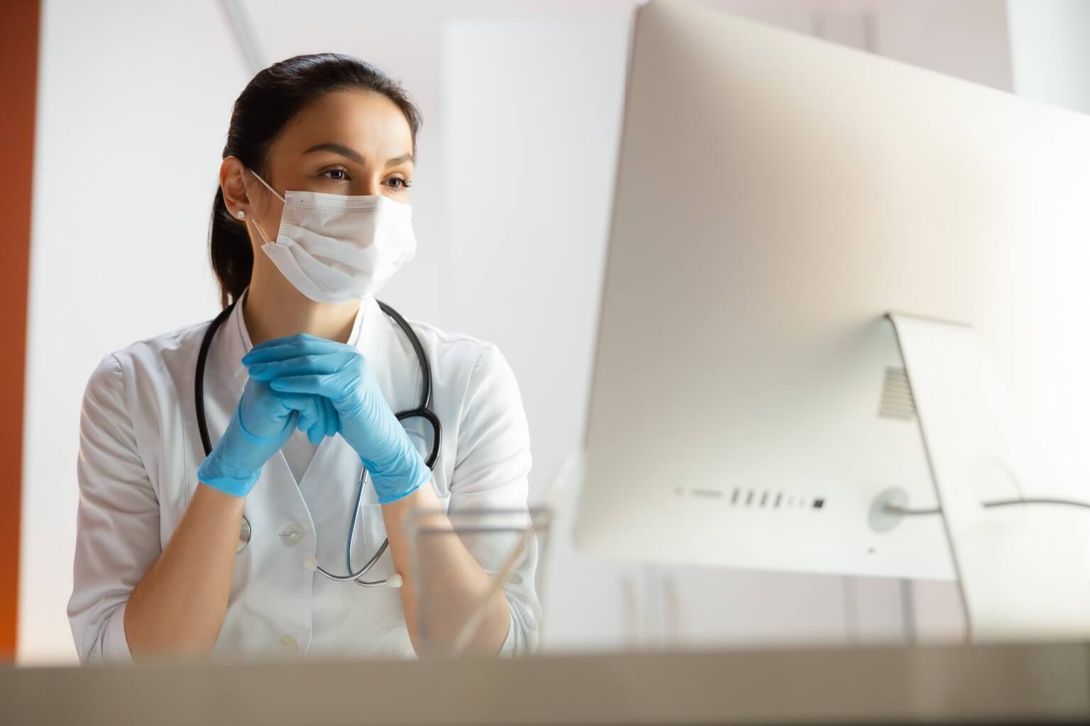 Nurse wearing a surgical mask at a computer
