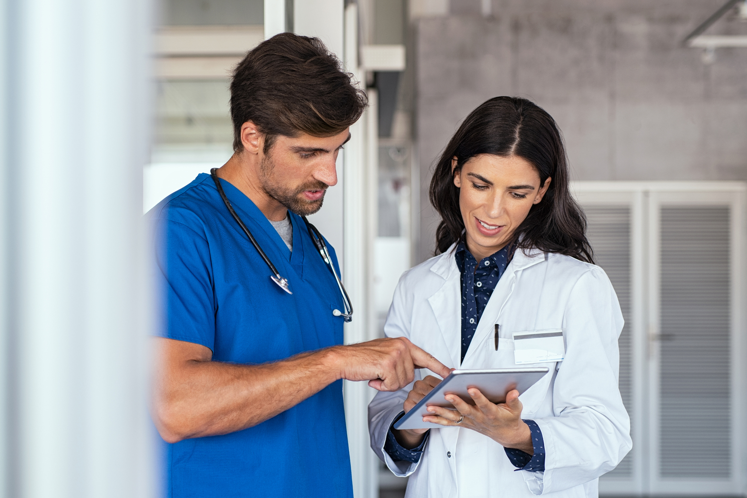 Pharmacist and nurse consulting a tablet