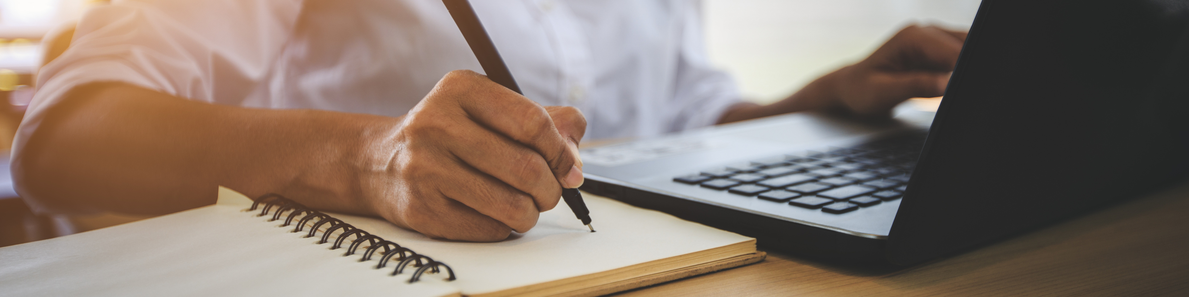 young woman on laptop and taking notes