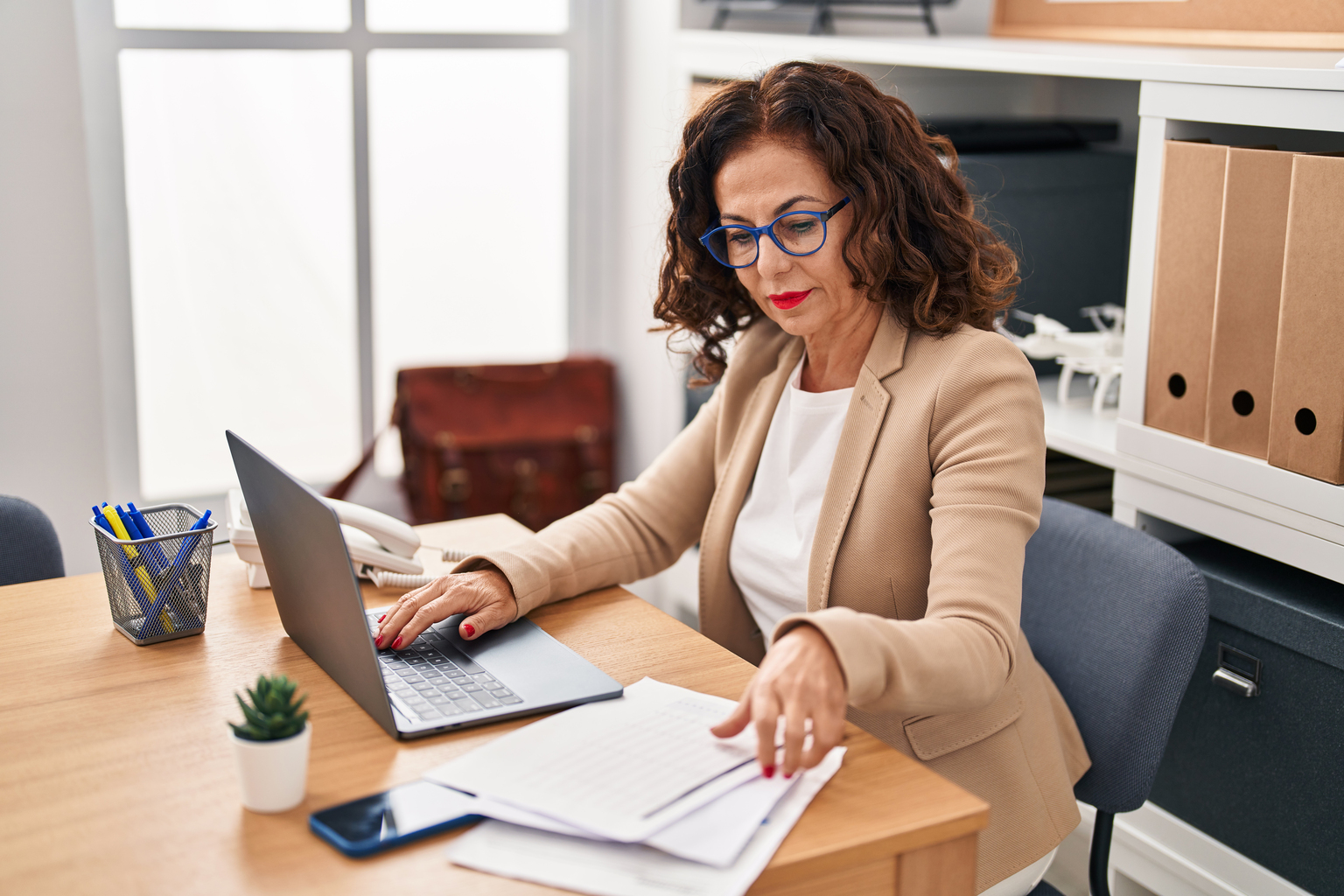 Middle age hispanic woman working with laptop and documents at the office