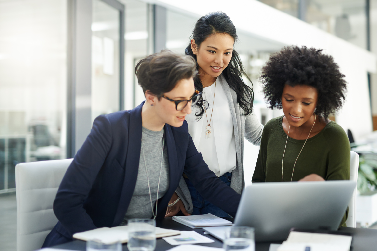 Three Businesswomen smilingly looking at the laptop.