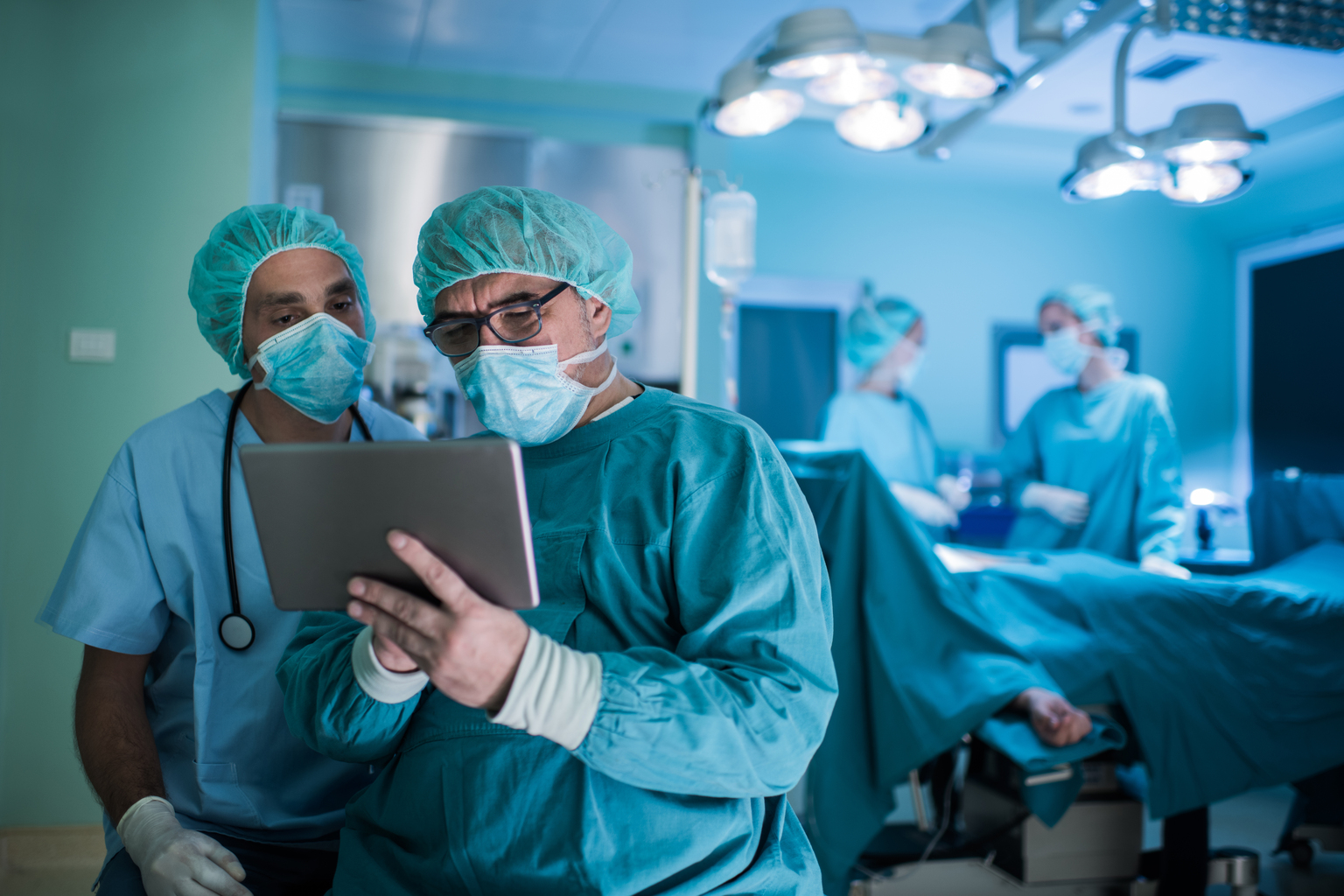 Dwóch lekarzy czyta coś na tablecie w sali operacyjnej w szpitalu, który wdrożył ustawę o jakości