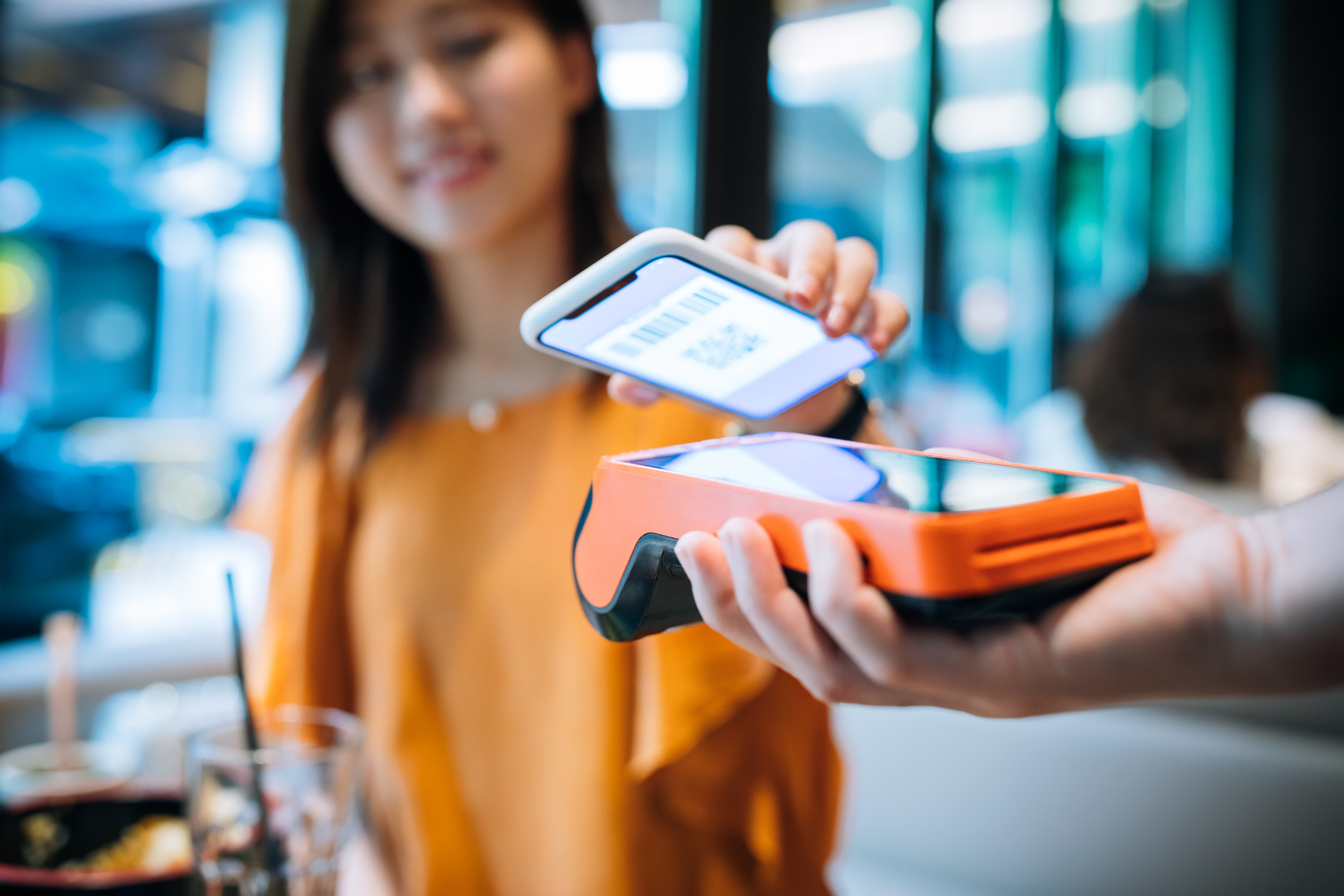 Young woman paying with smartphone in a cafe