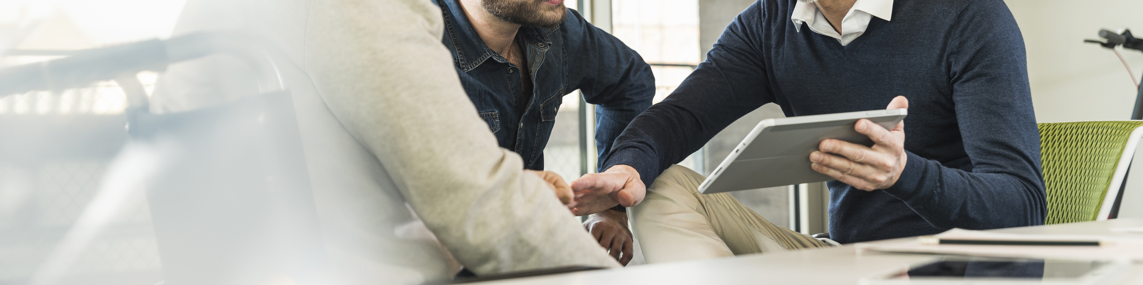 Three businessmen having a meeting in office sharing a tablet