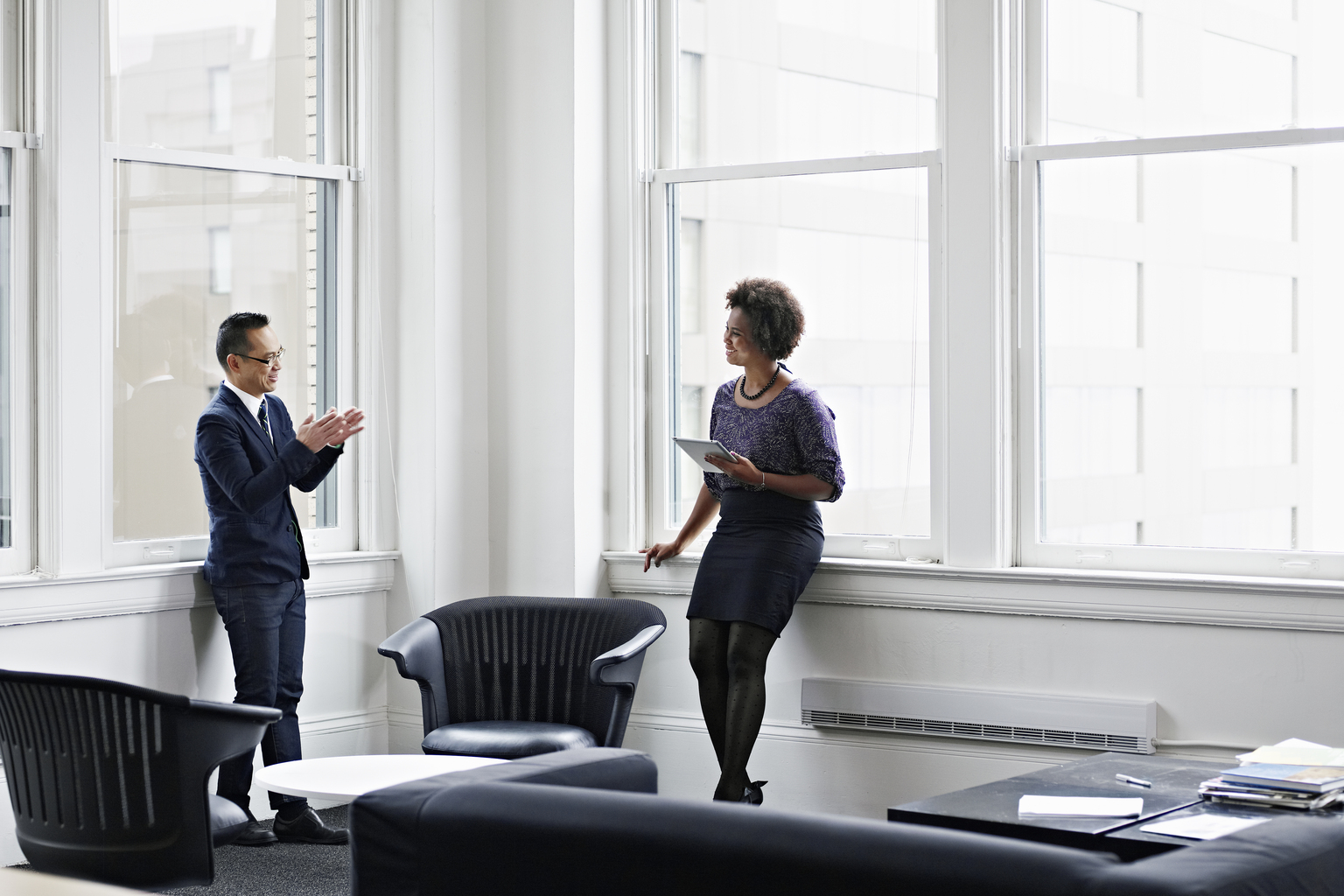 Smiling businesswoman holding digital tablet in discussing project with businessman in office