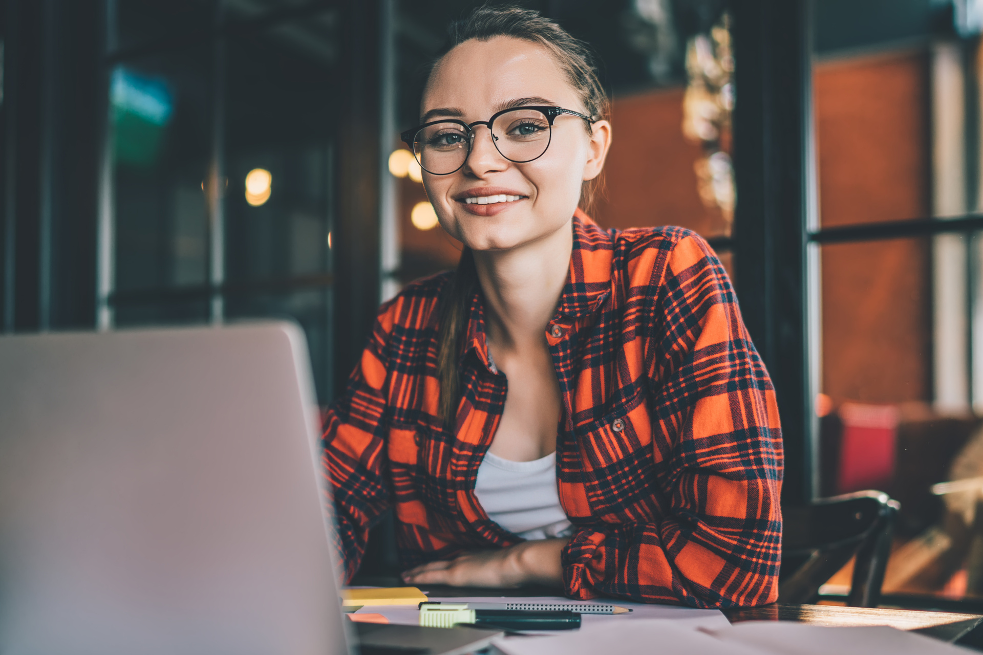 Smiling casual woman with laptop in cafe